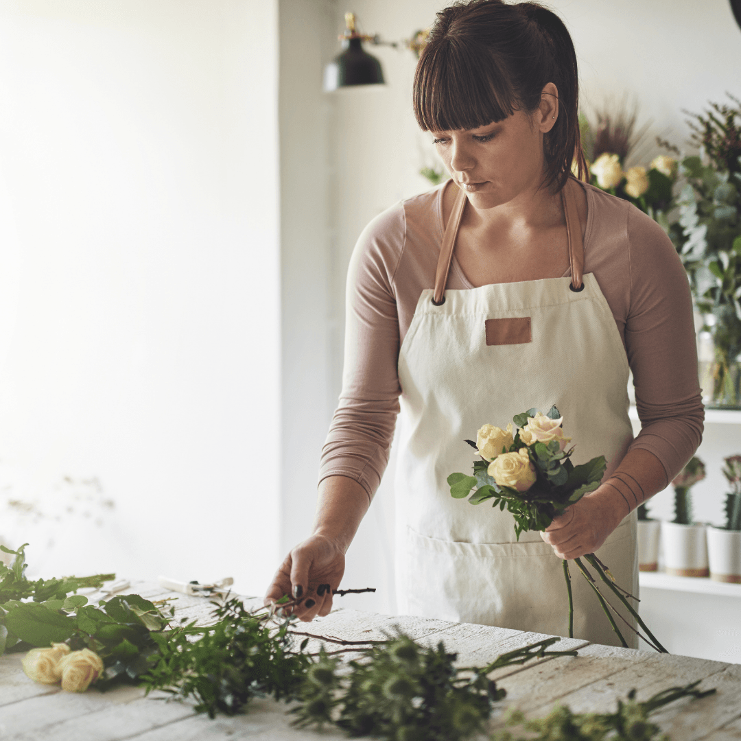 A woman in an apron is holding a bouquet of flowers.