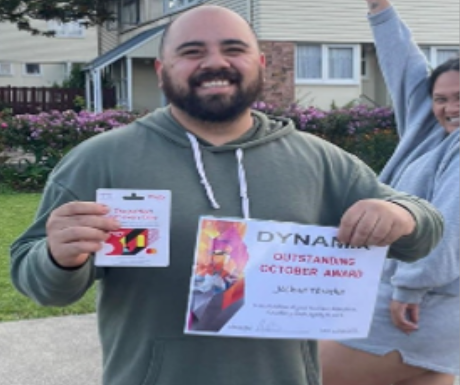 A man in a green hoodie is holding a dynama outstanding october award
