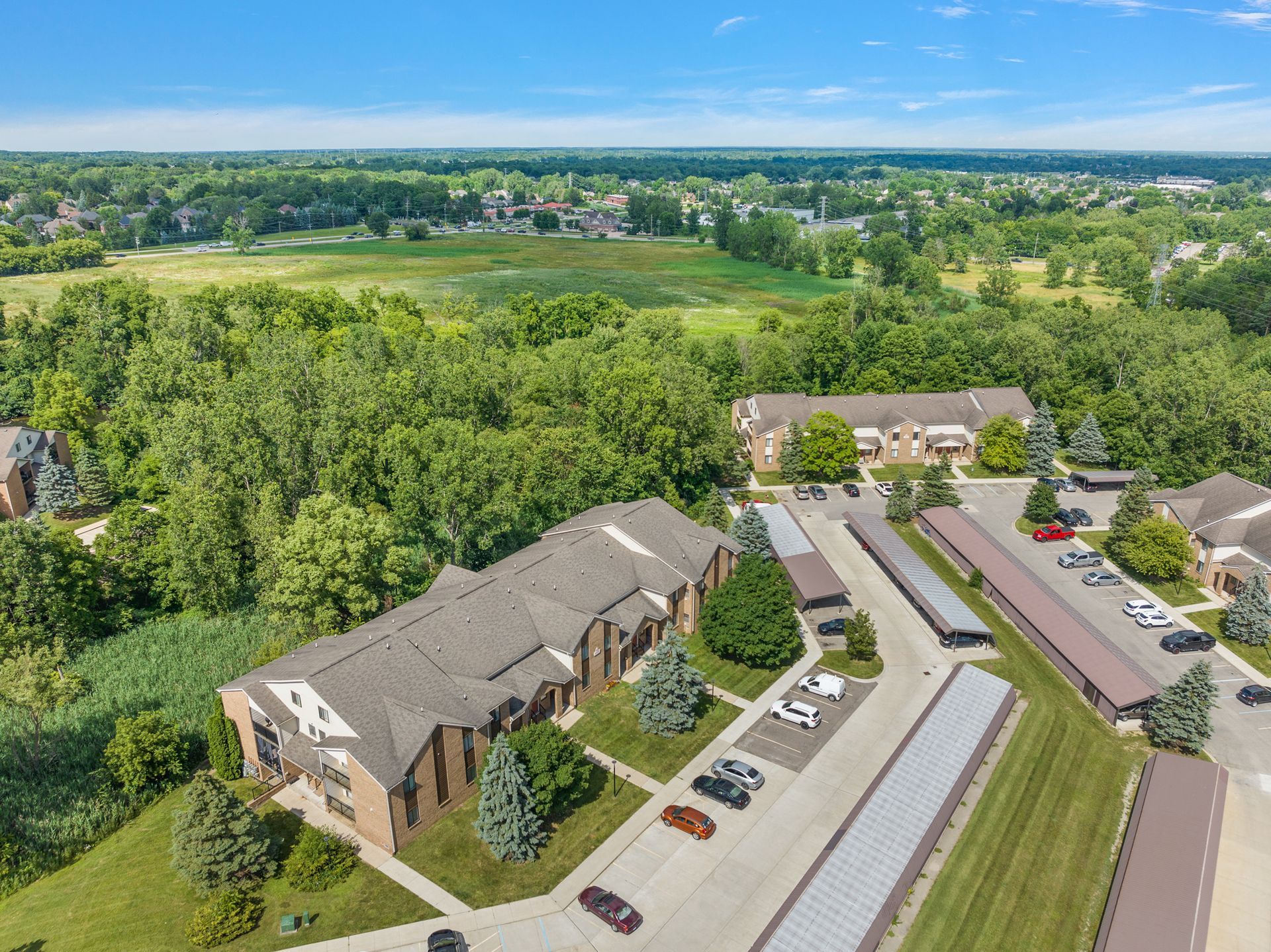 An aerial view of a large apartment complex surrounded by trees and a parking lot.