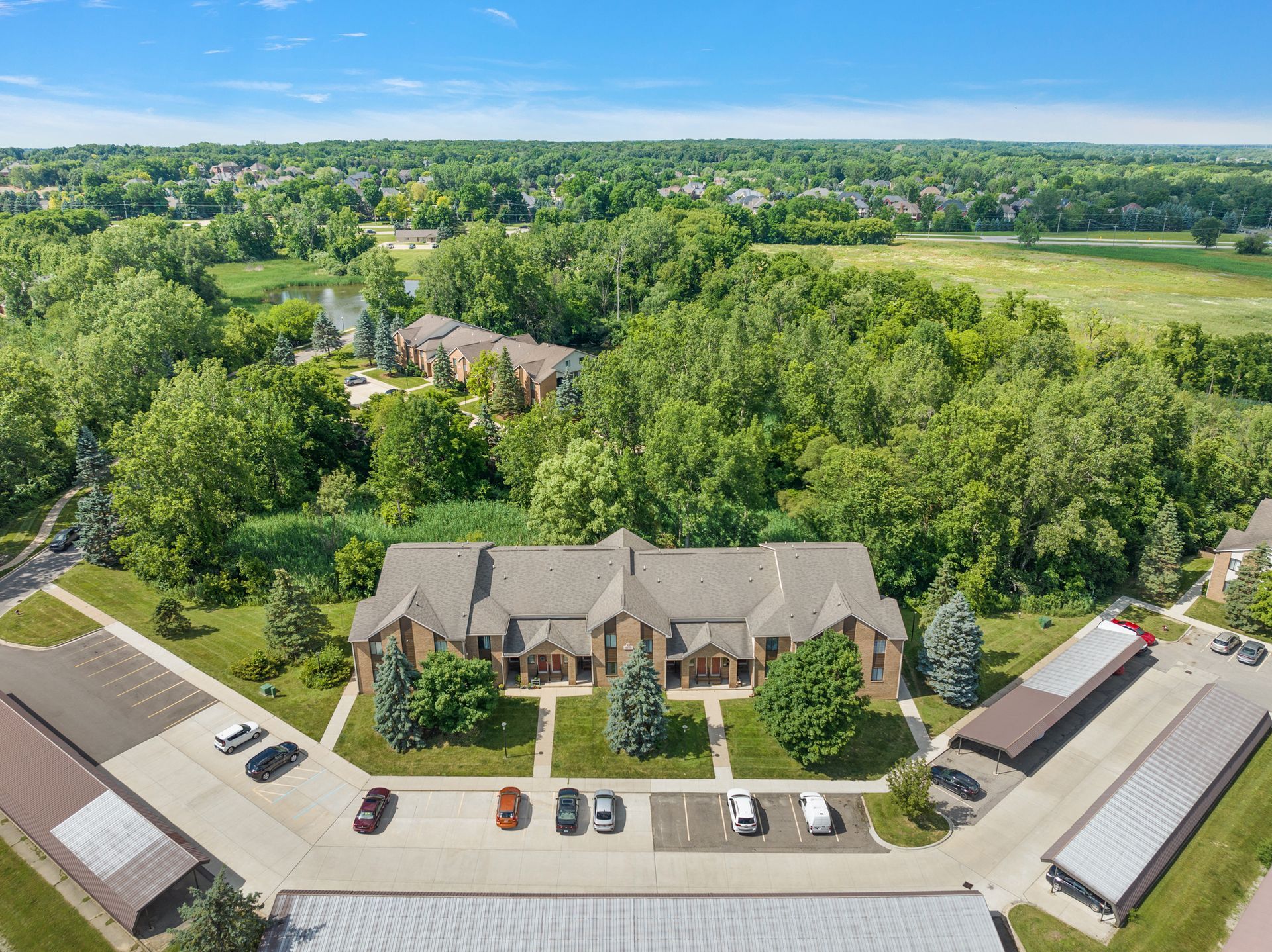 An aerial view of a large apartment complex surrounded by trees and a parking lot.