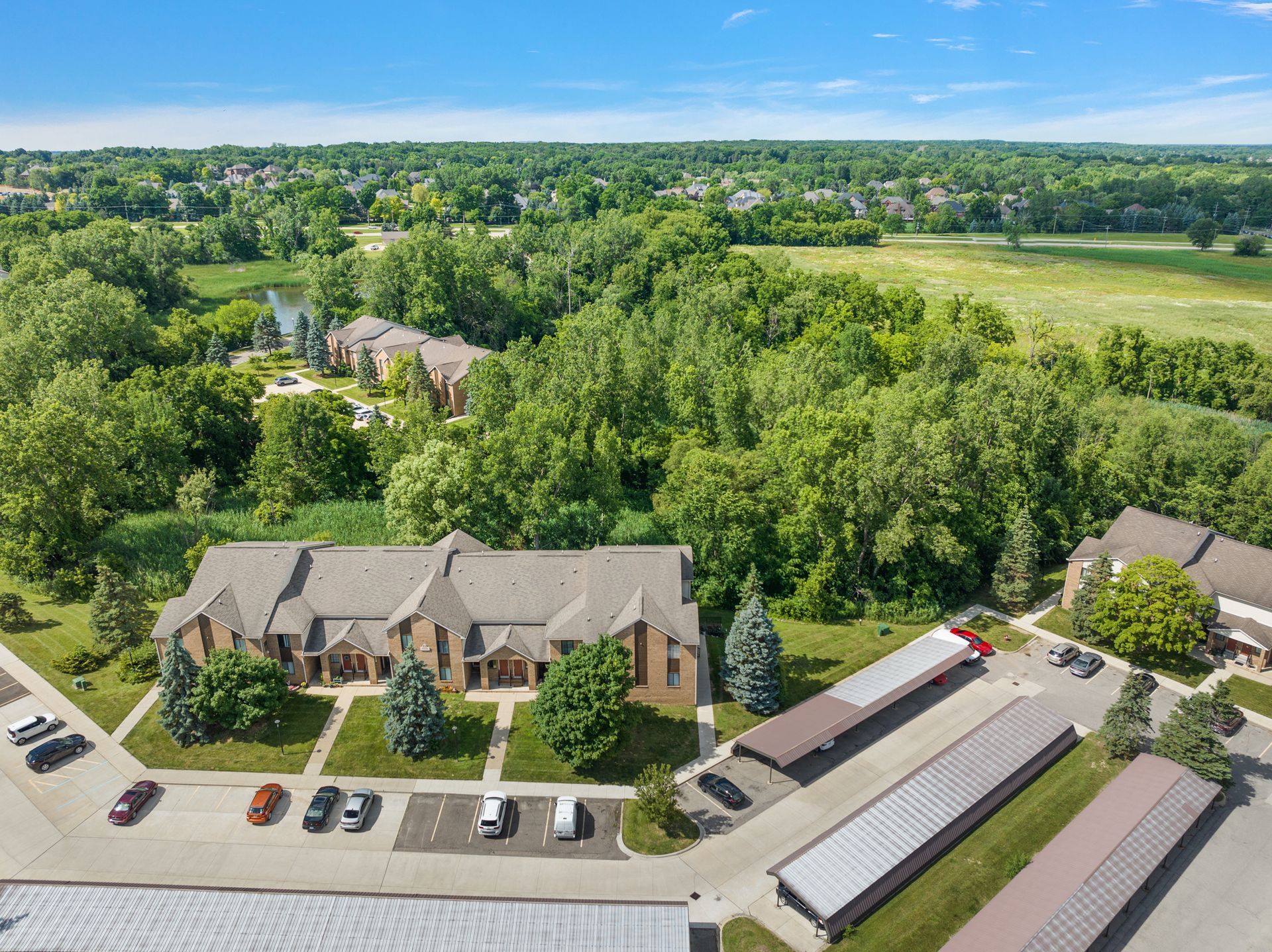 An aerial view of a apartment complex surrounded by trees and a parking lot.