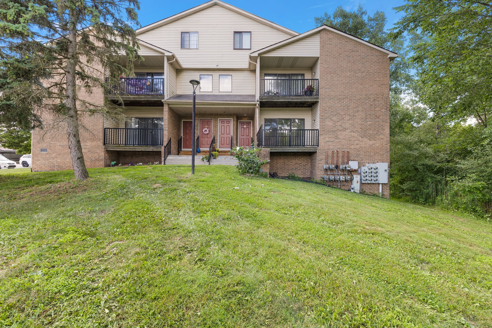 A large apartment building is sitting on top of a grassy hill.