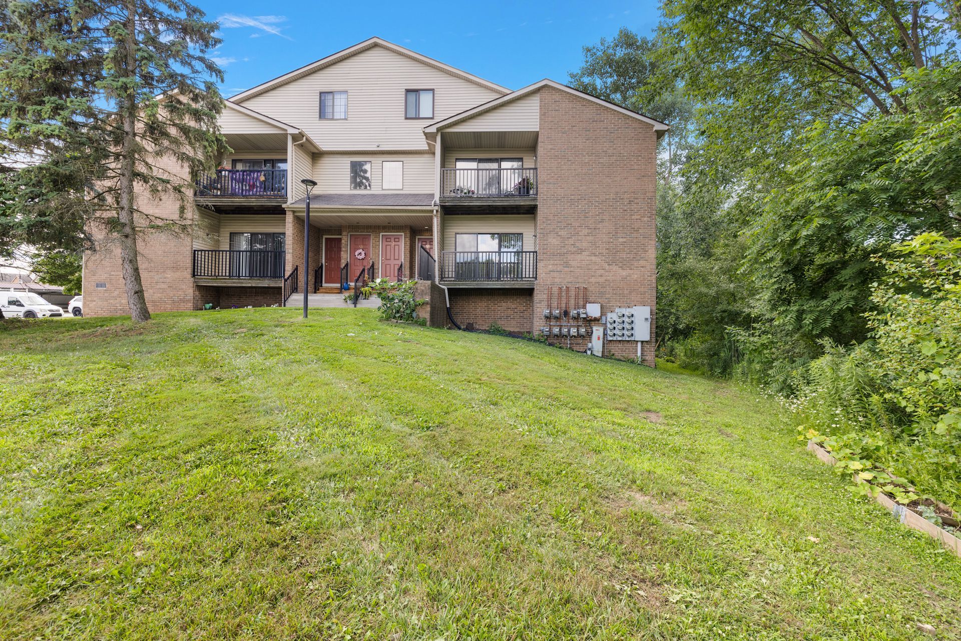 A large apartment building is sitting on top of a grassy hill.