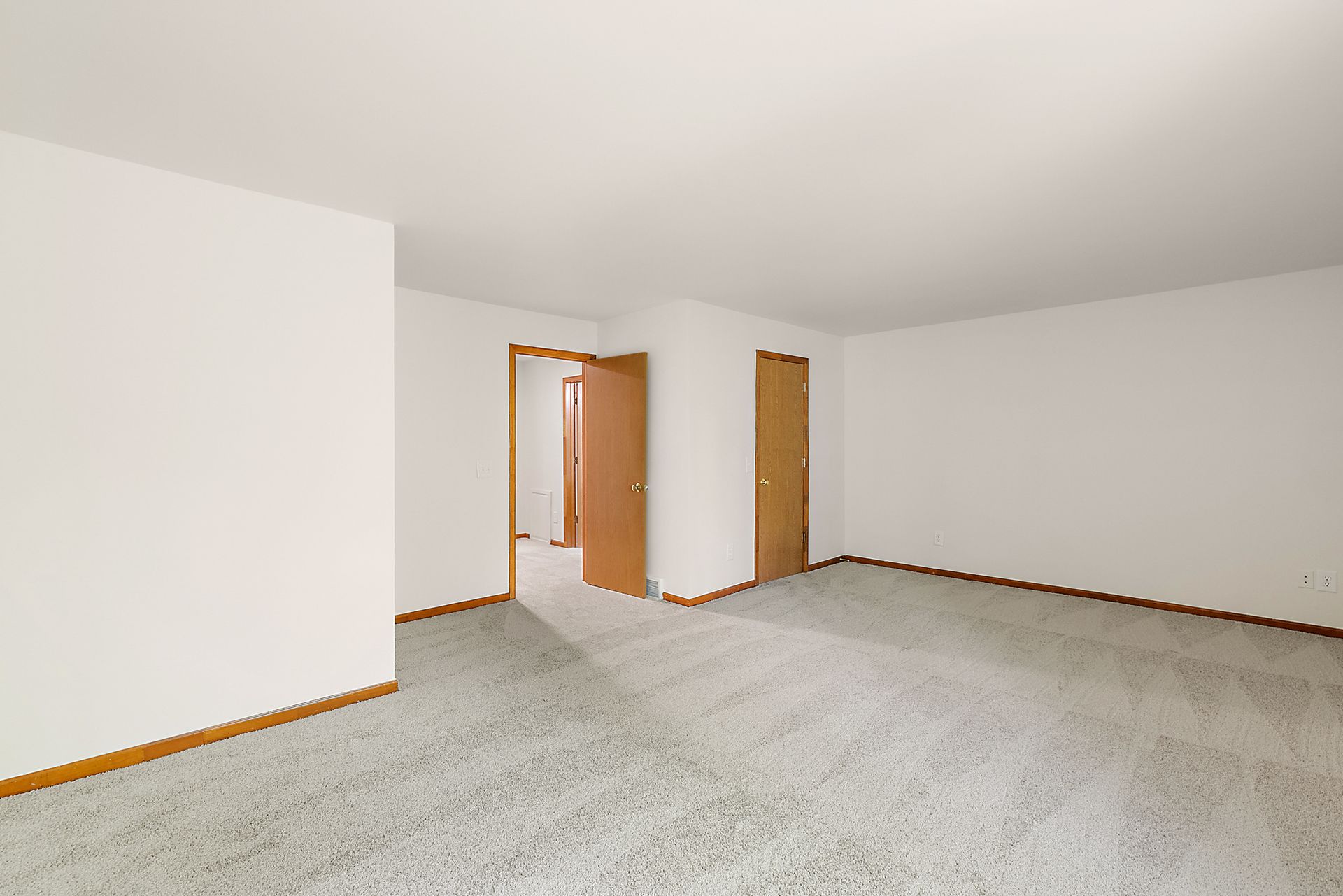 An empty room with a carpeted floor and white walls