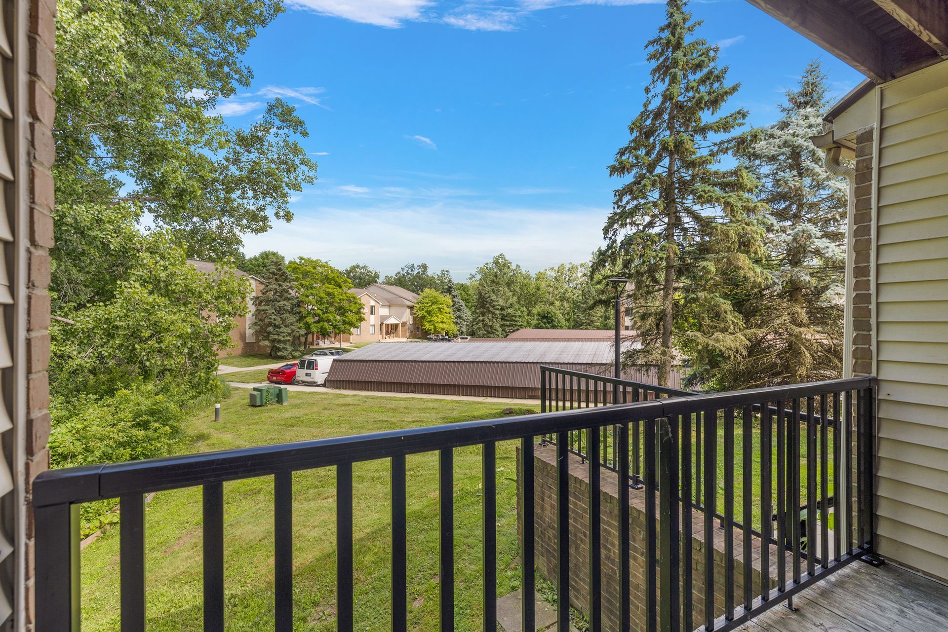 There is a balcony with a view of a field and trees.