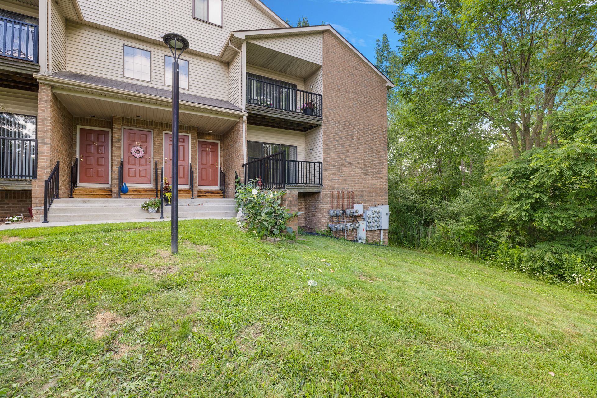 A large brick apartment building with a lush green lawn in front of it.