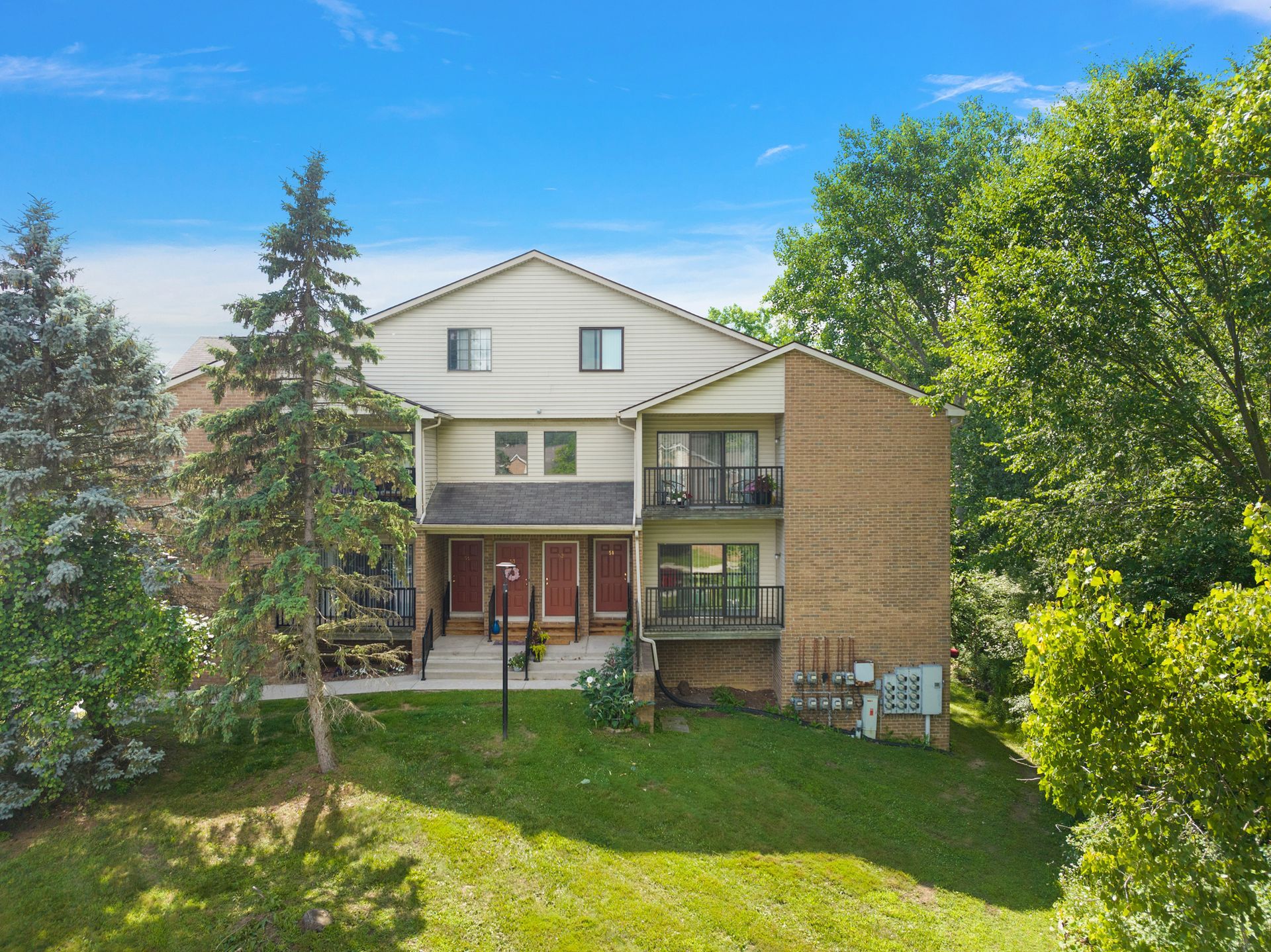 An aerial view of a large apartment building surrounded by trees and grass.
