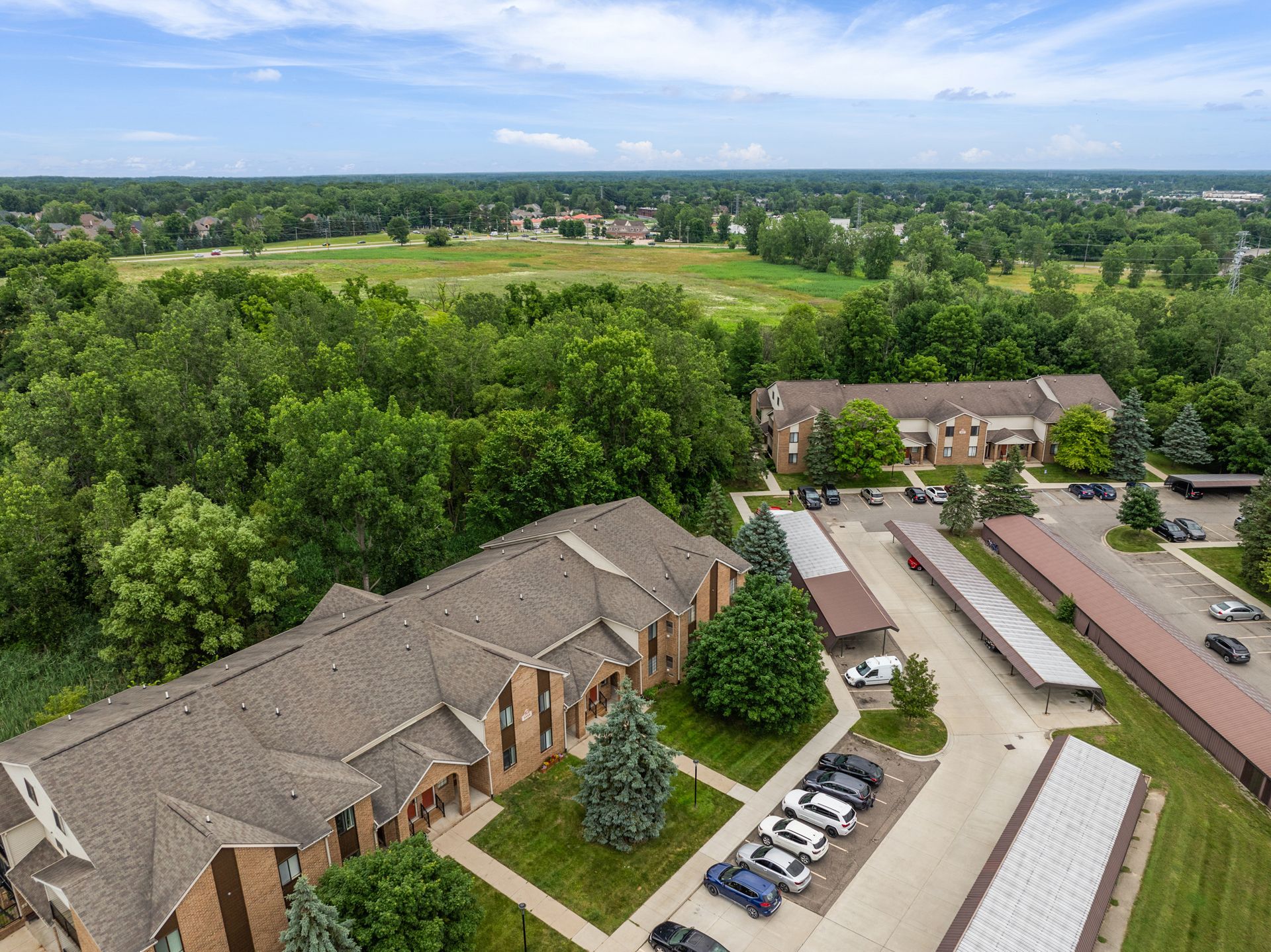 An aerial view of a large apartment complex surrounded by trees and a parking lot.