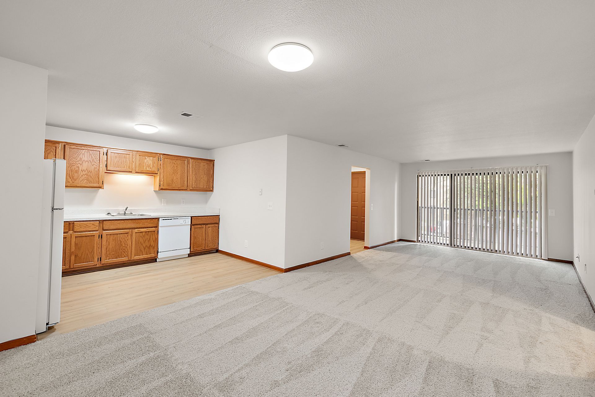 A living room with a kitchen and a sliding glass door.