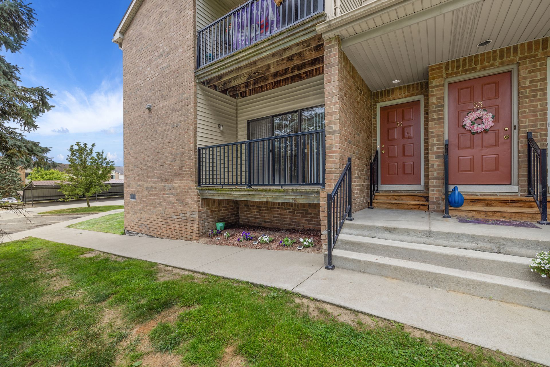 A brick apartment building with two red doors and a balcony.