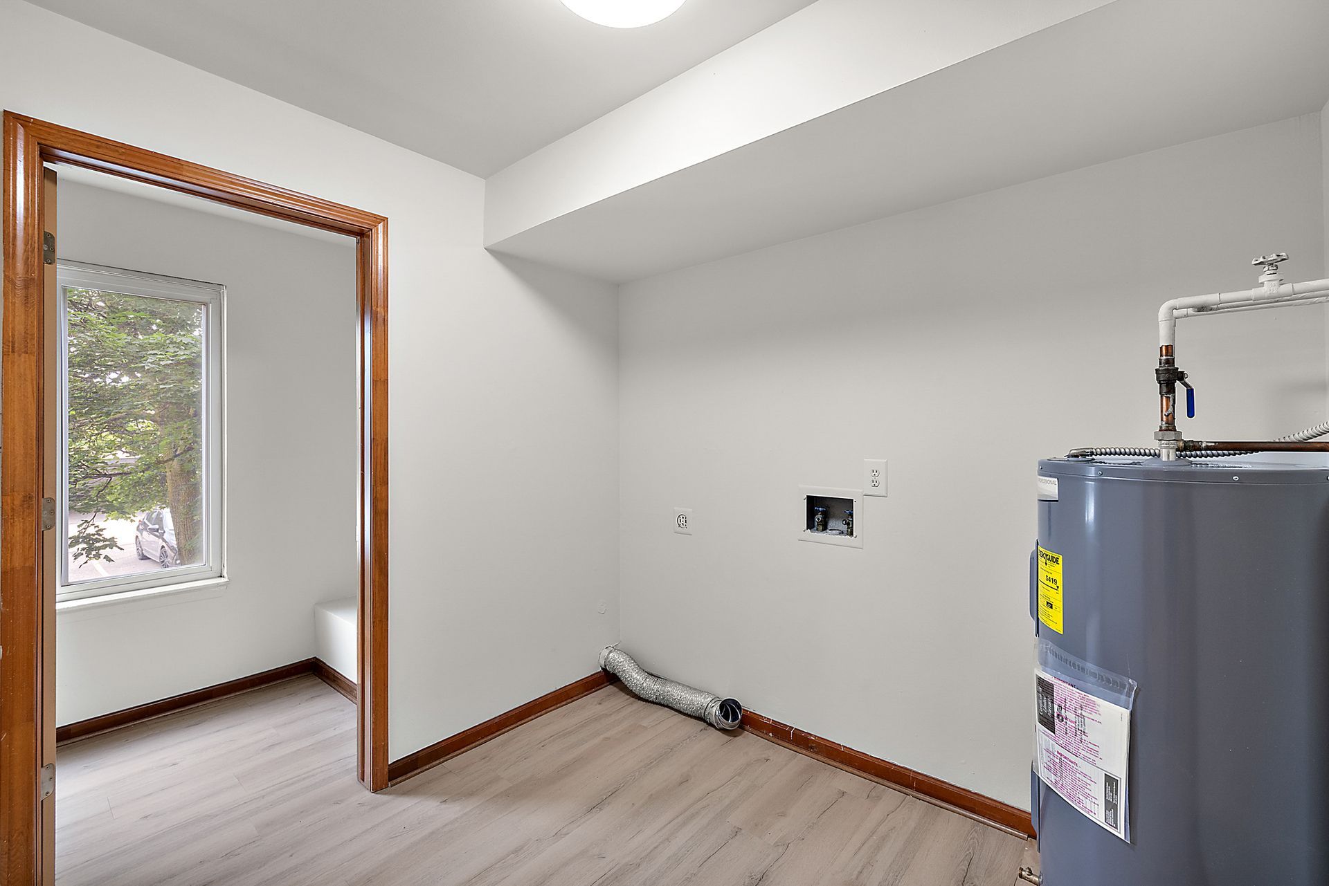 A laundry room with a water heater and a window.