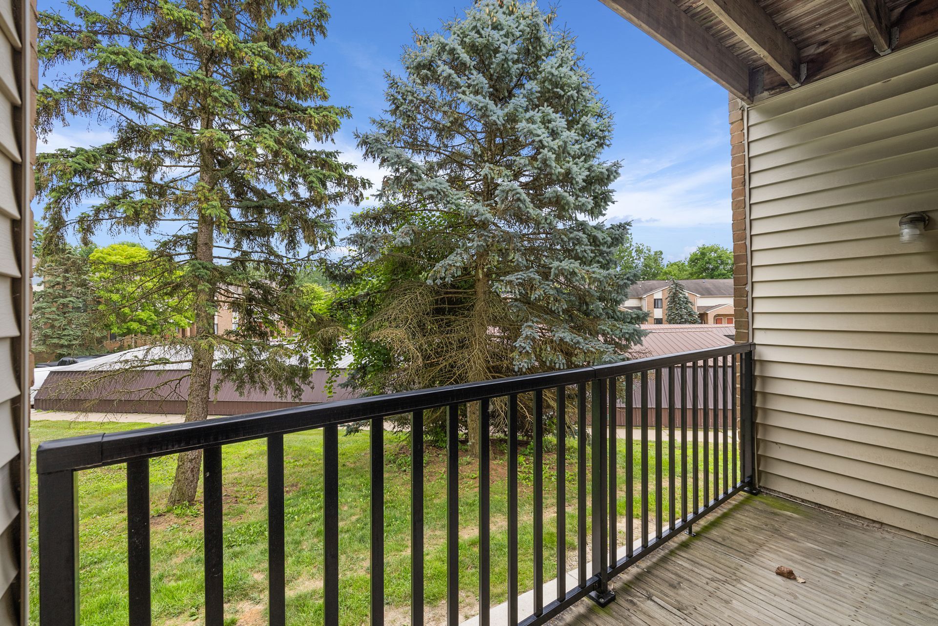 A balcony with a black railing and trees in the background.