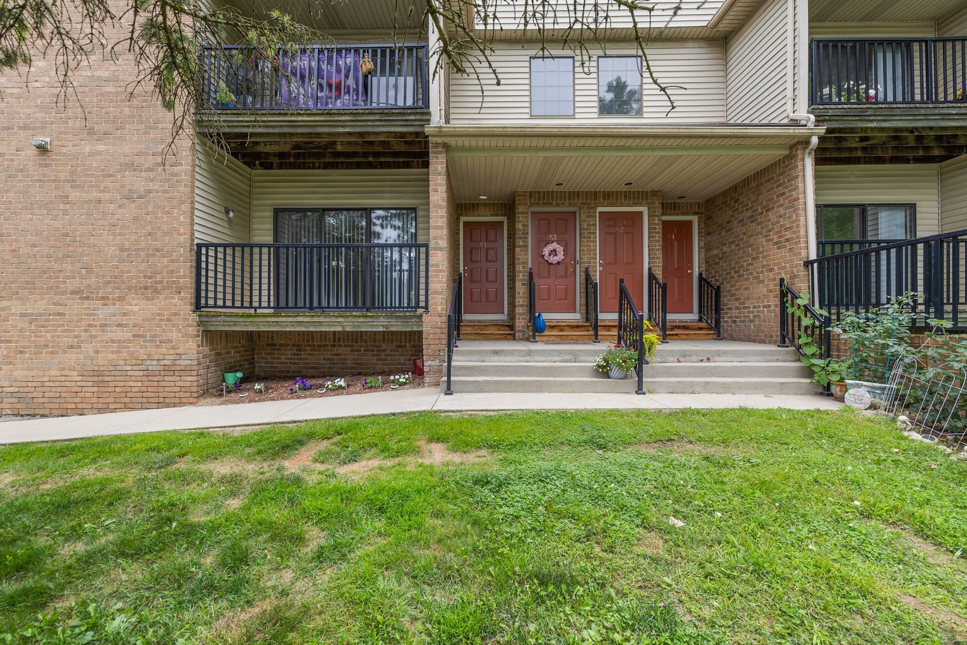 A brick apartment building with a lush green lawn in front of it.
