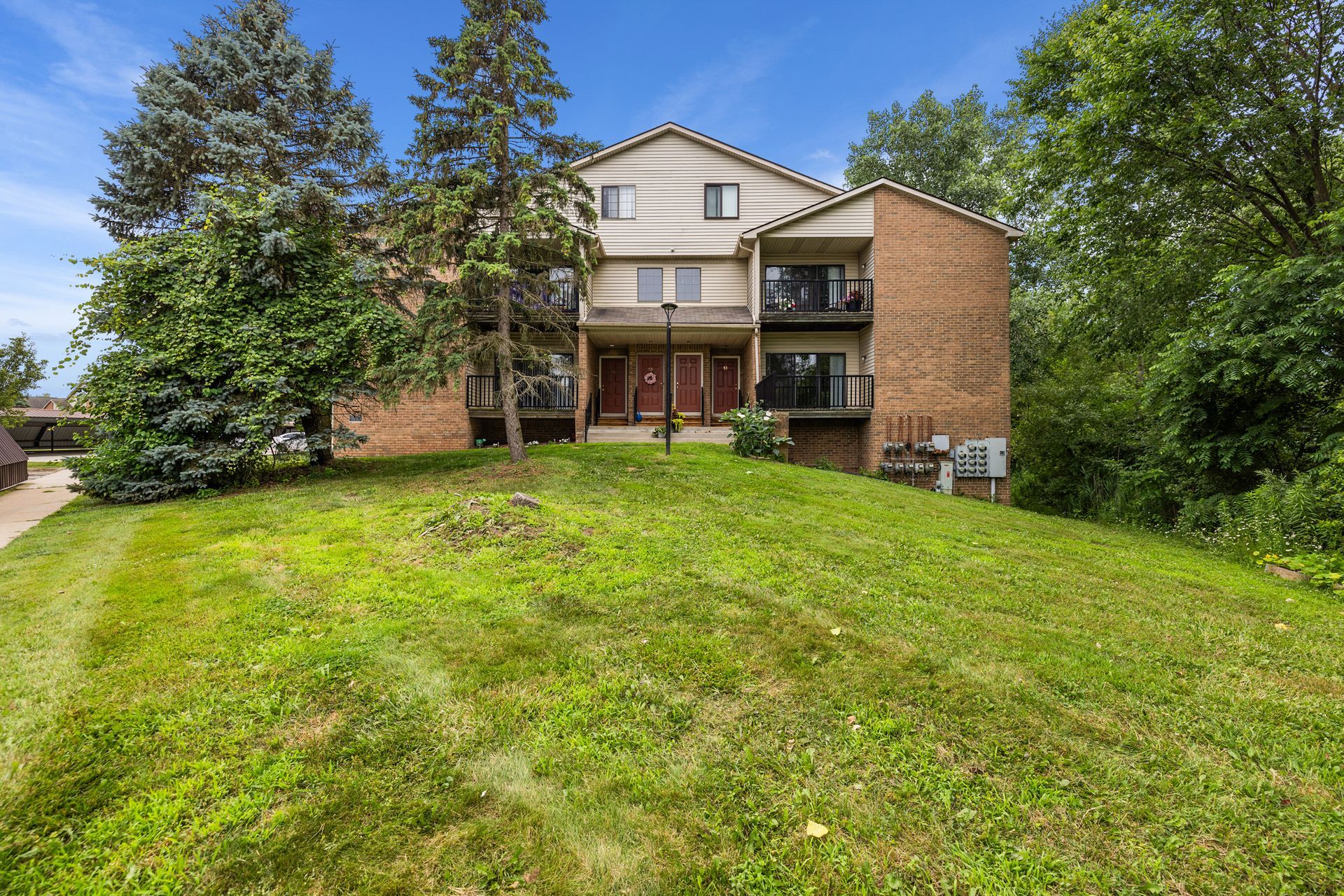 A large brick apartment building with a lush green lawn in front of it.