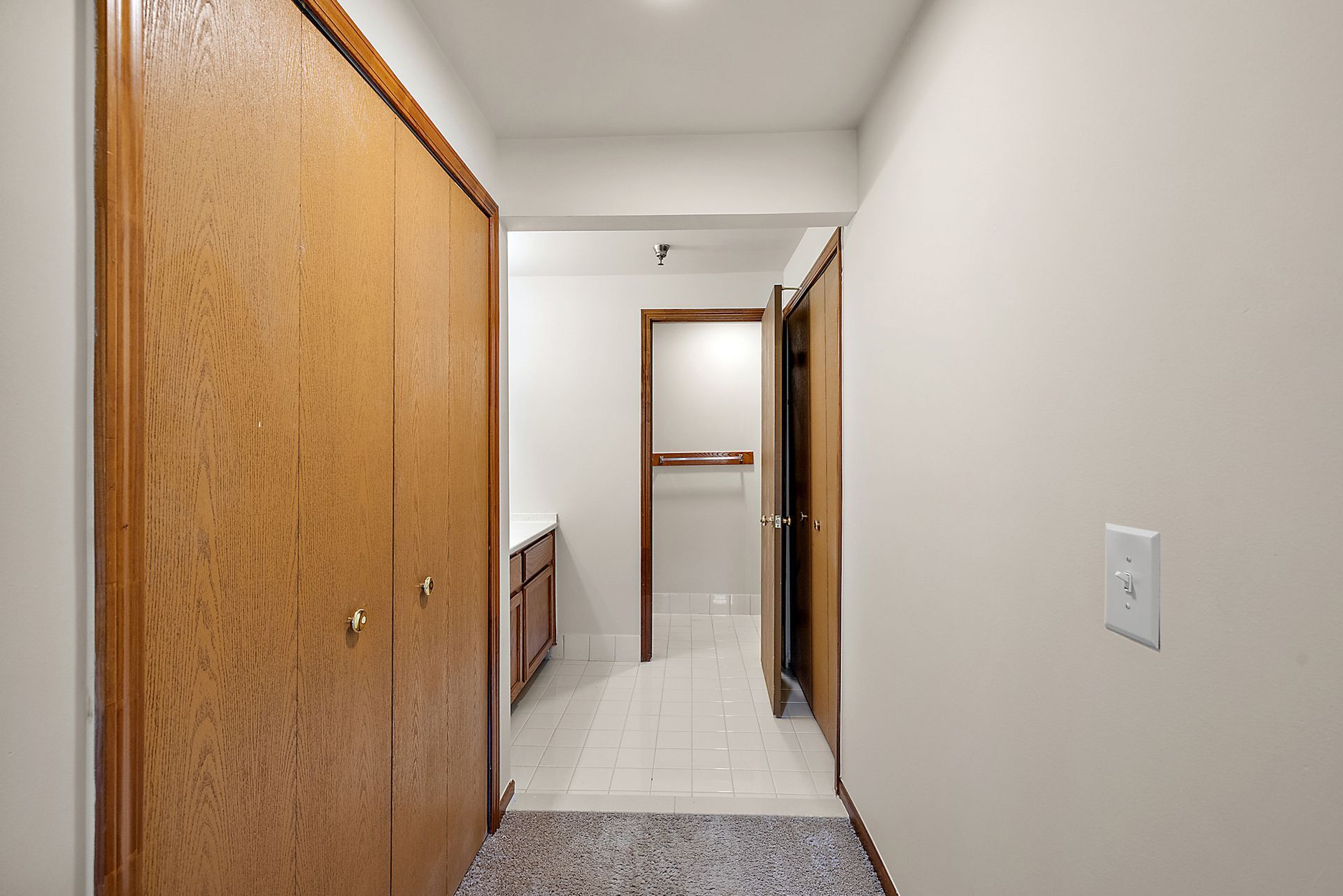 A hallway in a house with a closet and a bathroom.