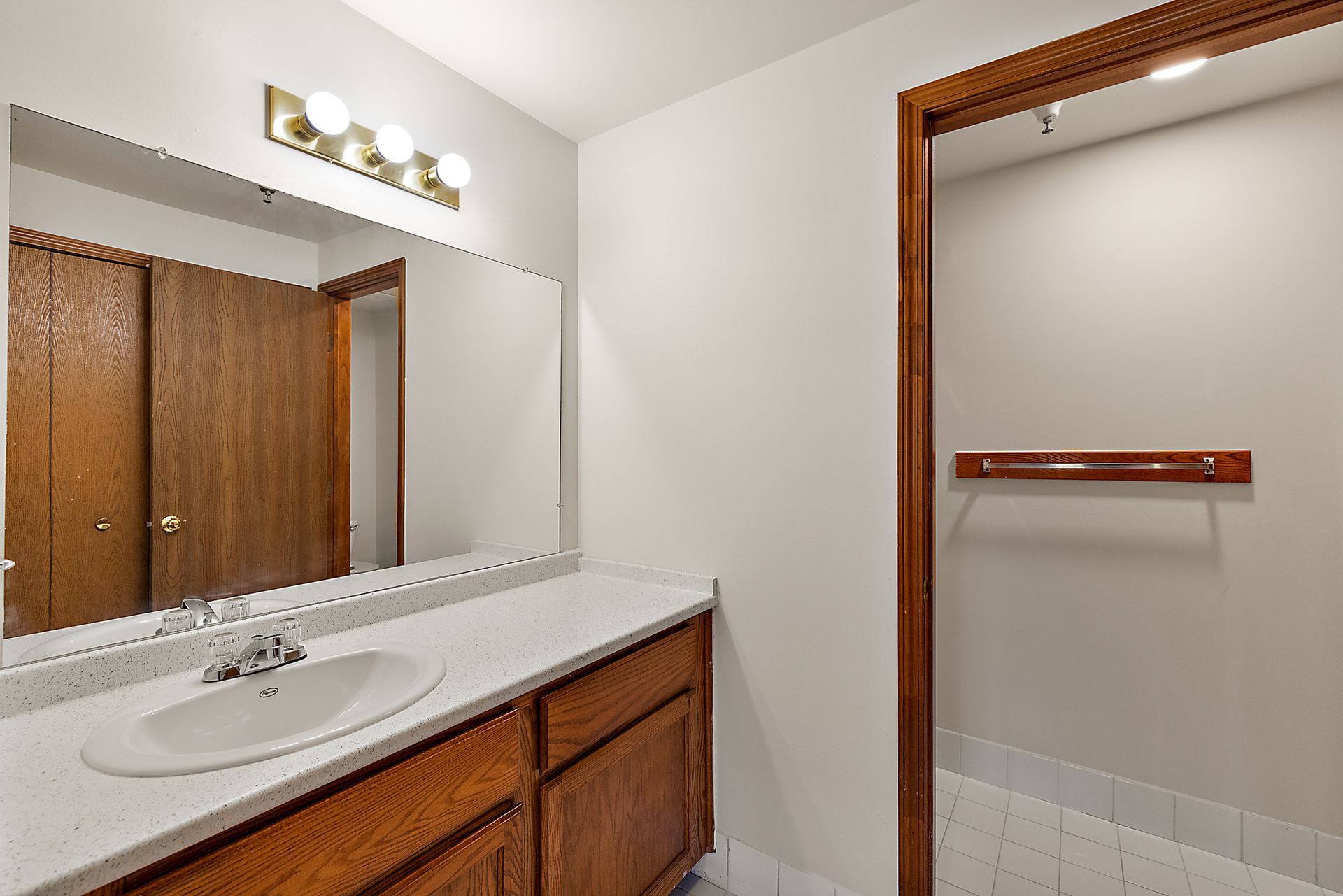 A bathroom with a sink , mirror and wooden cabinets.