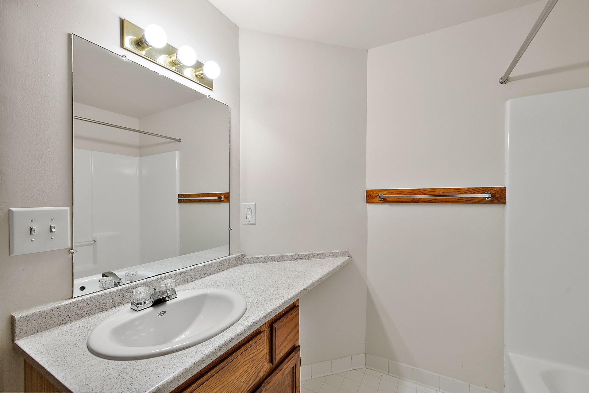 A bathroom with a sink , mirror and shower.