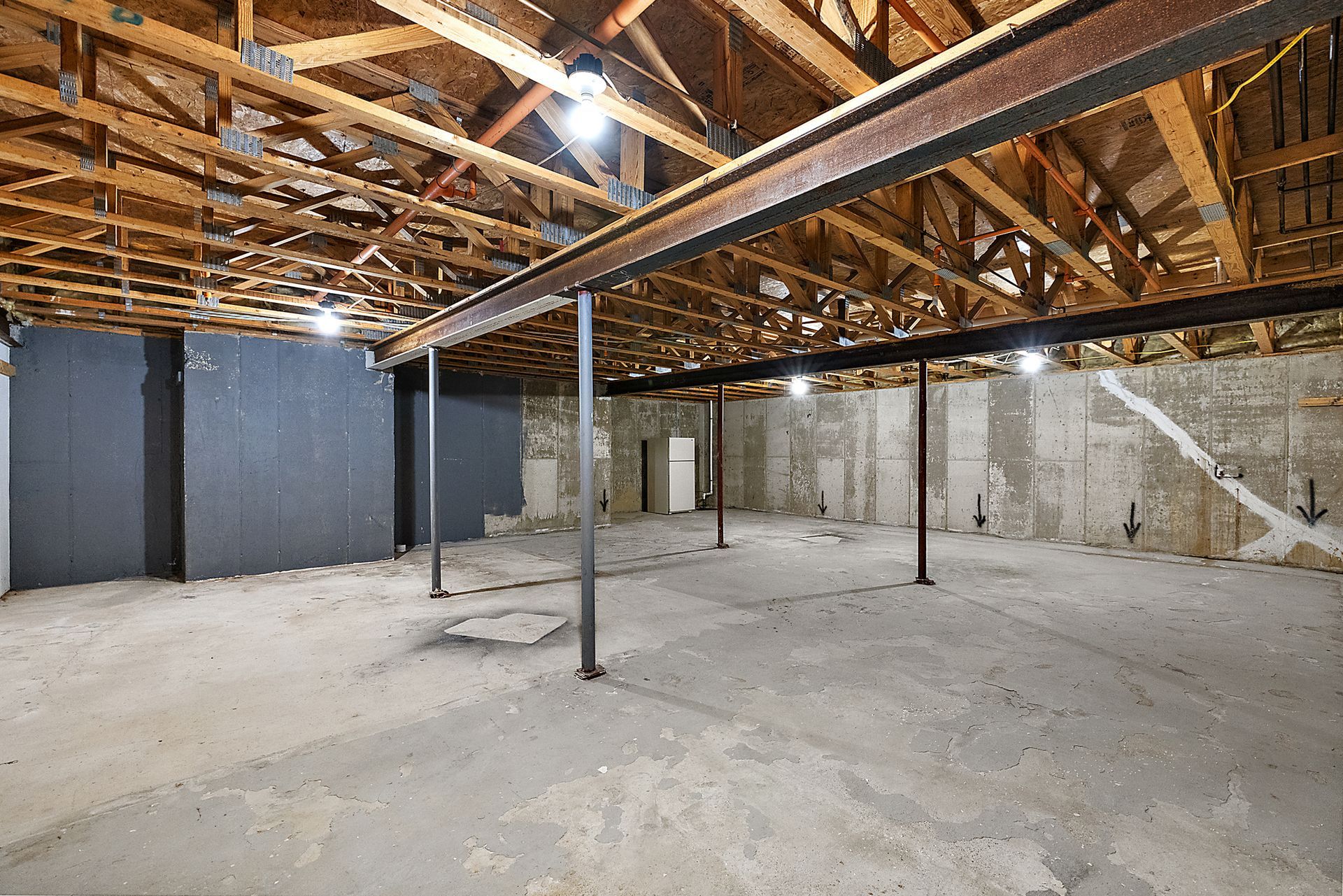 An empty basement with a wooden ceiling and concrete floor.