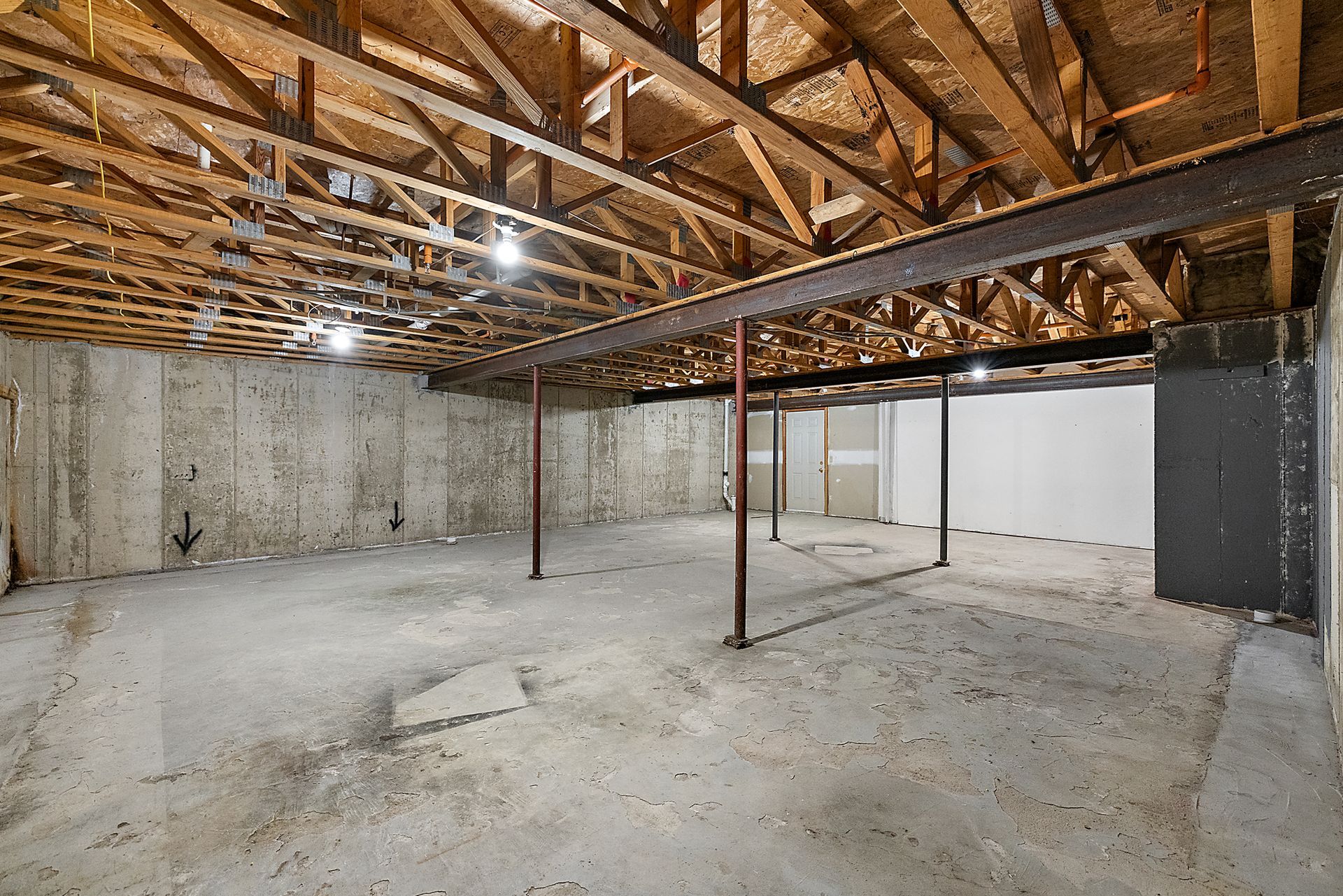 An empty basement with wooden beams and a concrete floor