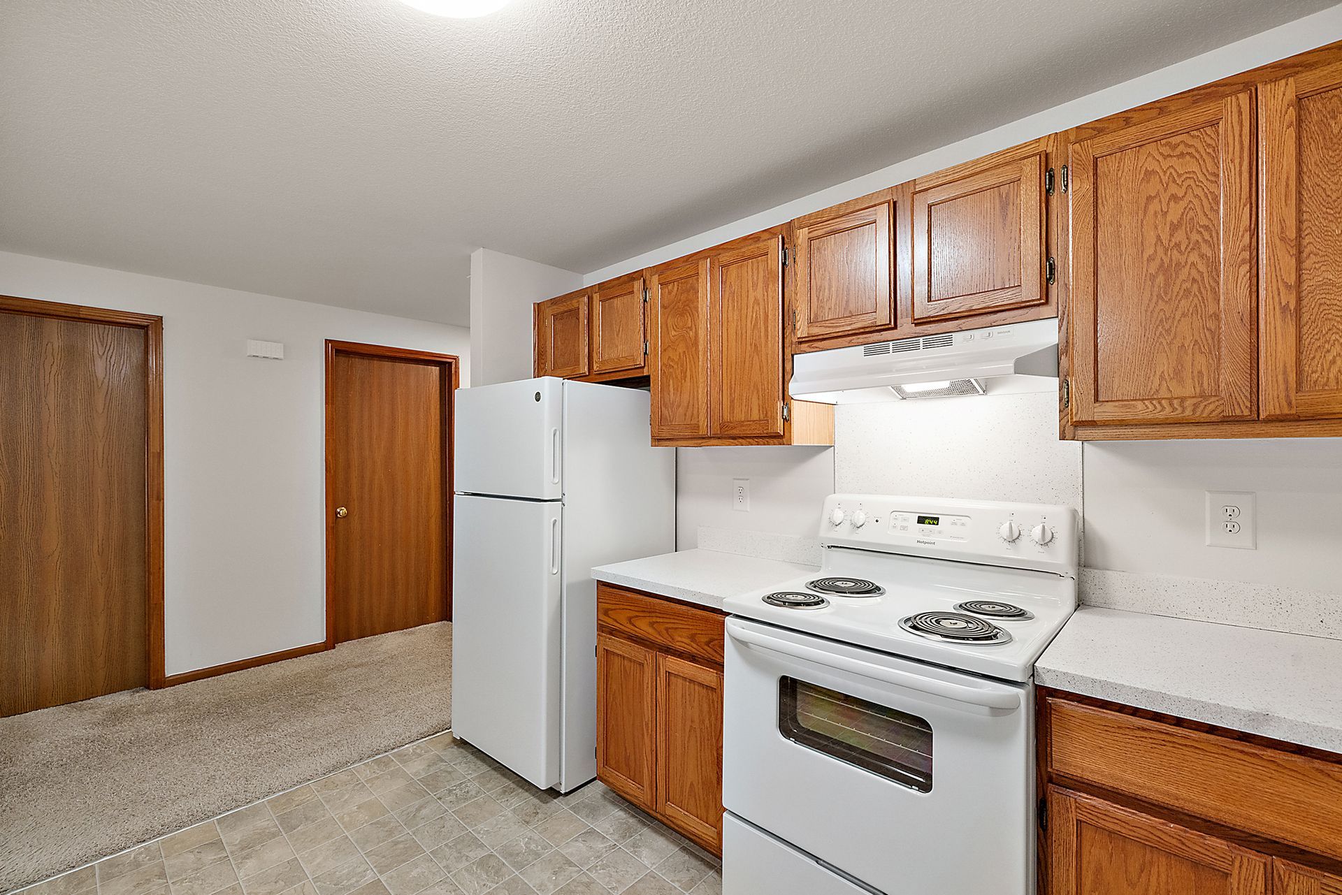 A kitchen with a stove , refrigerator , and wooden cabinets.