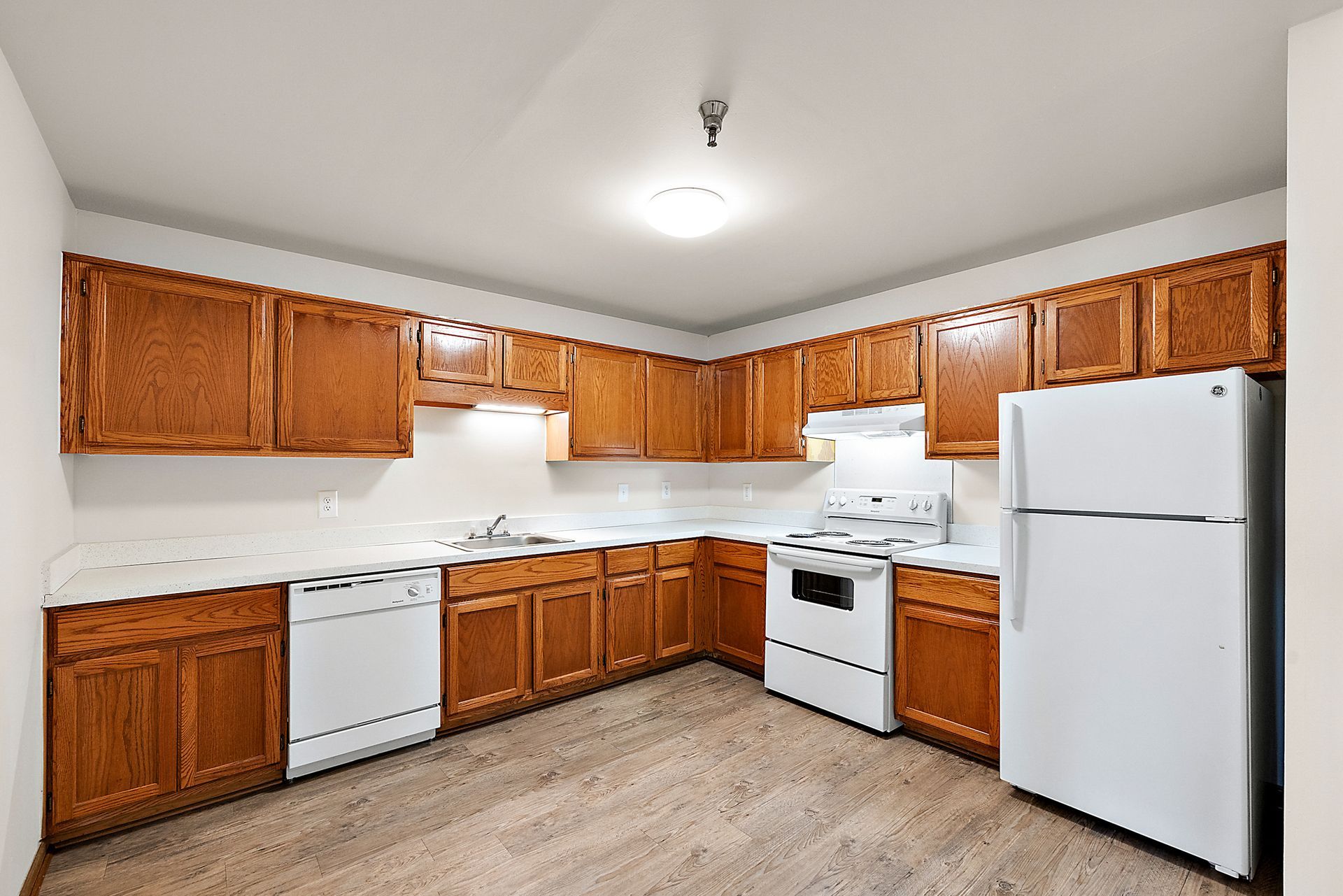 A kitchen with wooden cabinets , white appliances and a refrigerator.