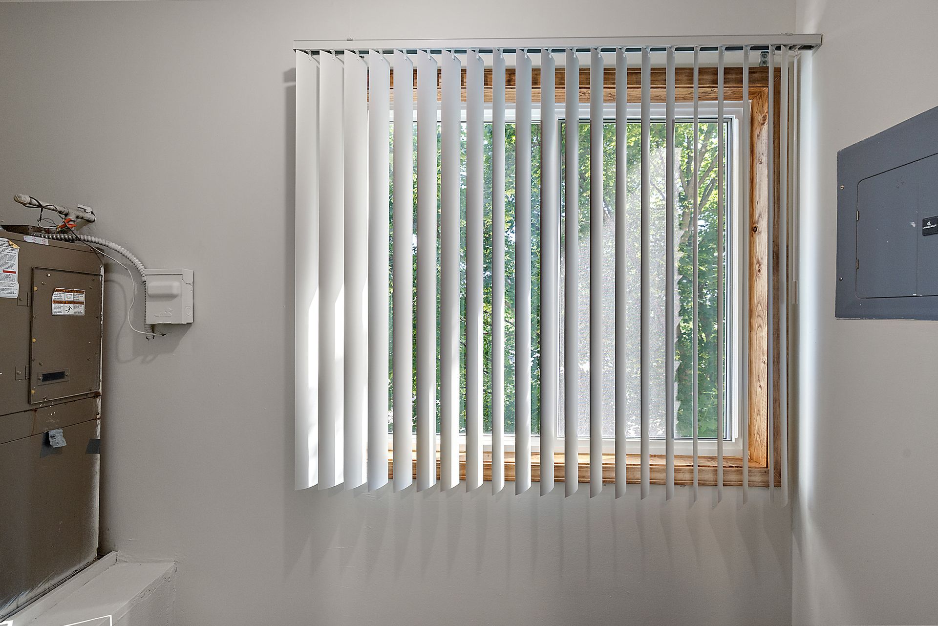 A room with a window and vertical blinds on it.