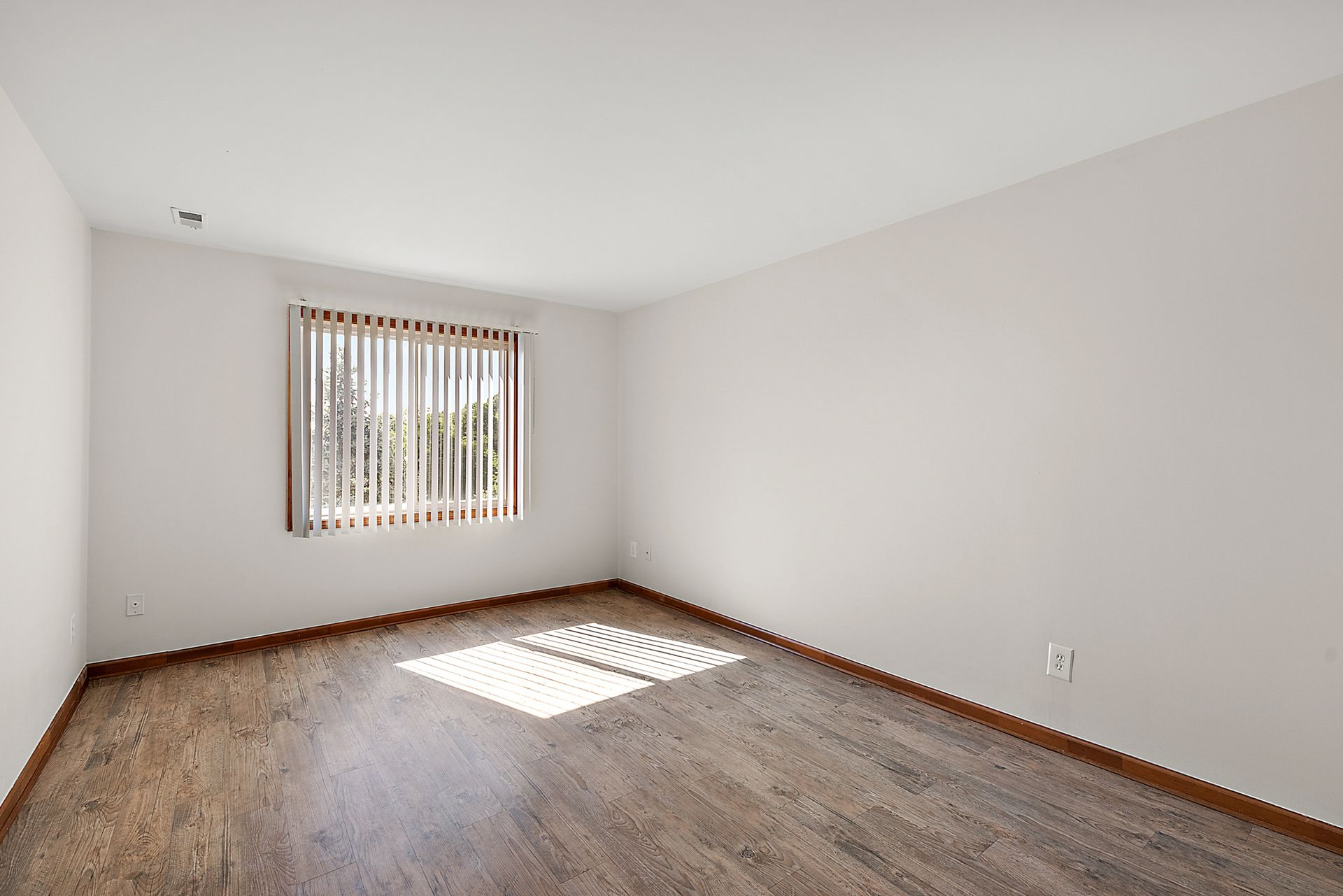 An empty living room with hardwood floors and a window.