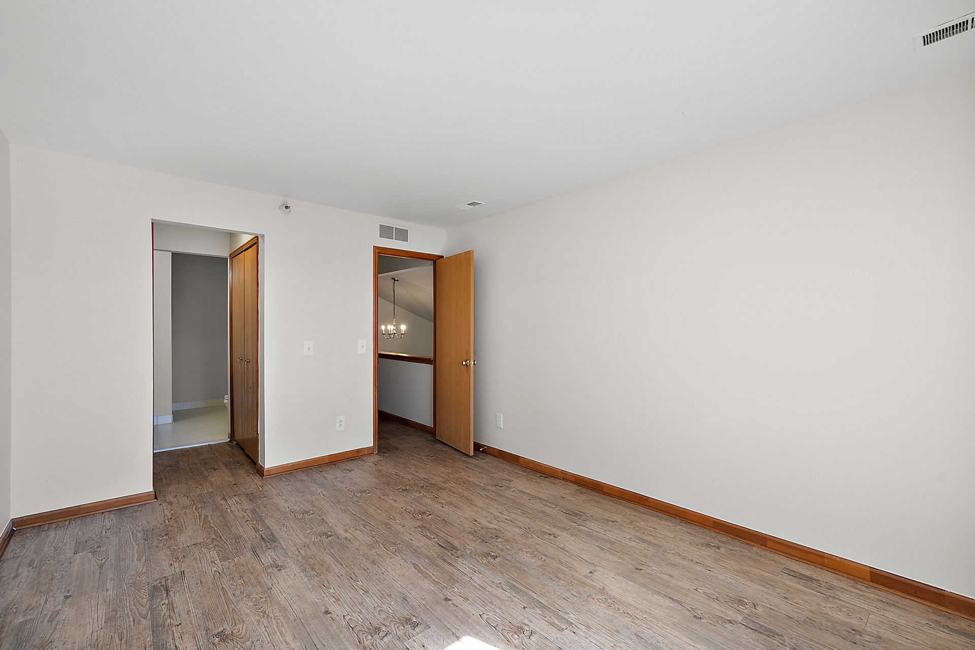 An empty room with a wooden floor and white walls