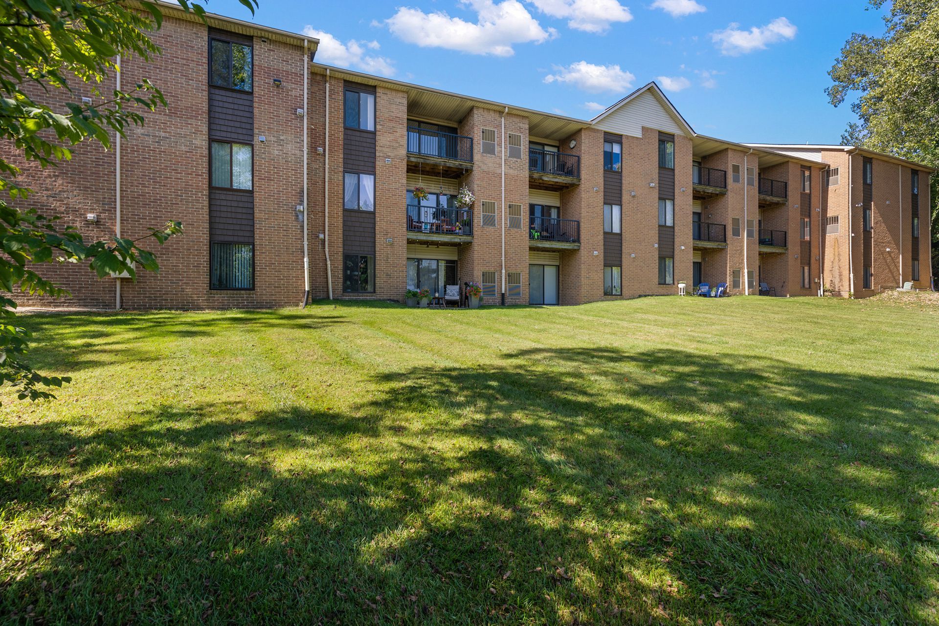 A large brick apartment building with a lush green lawn in front of it.