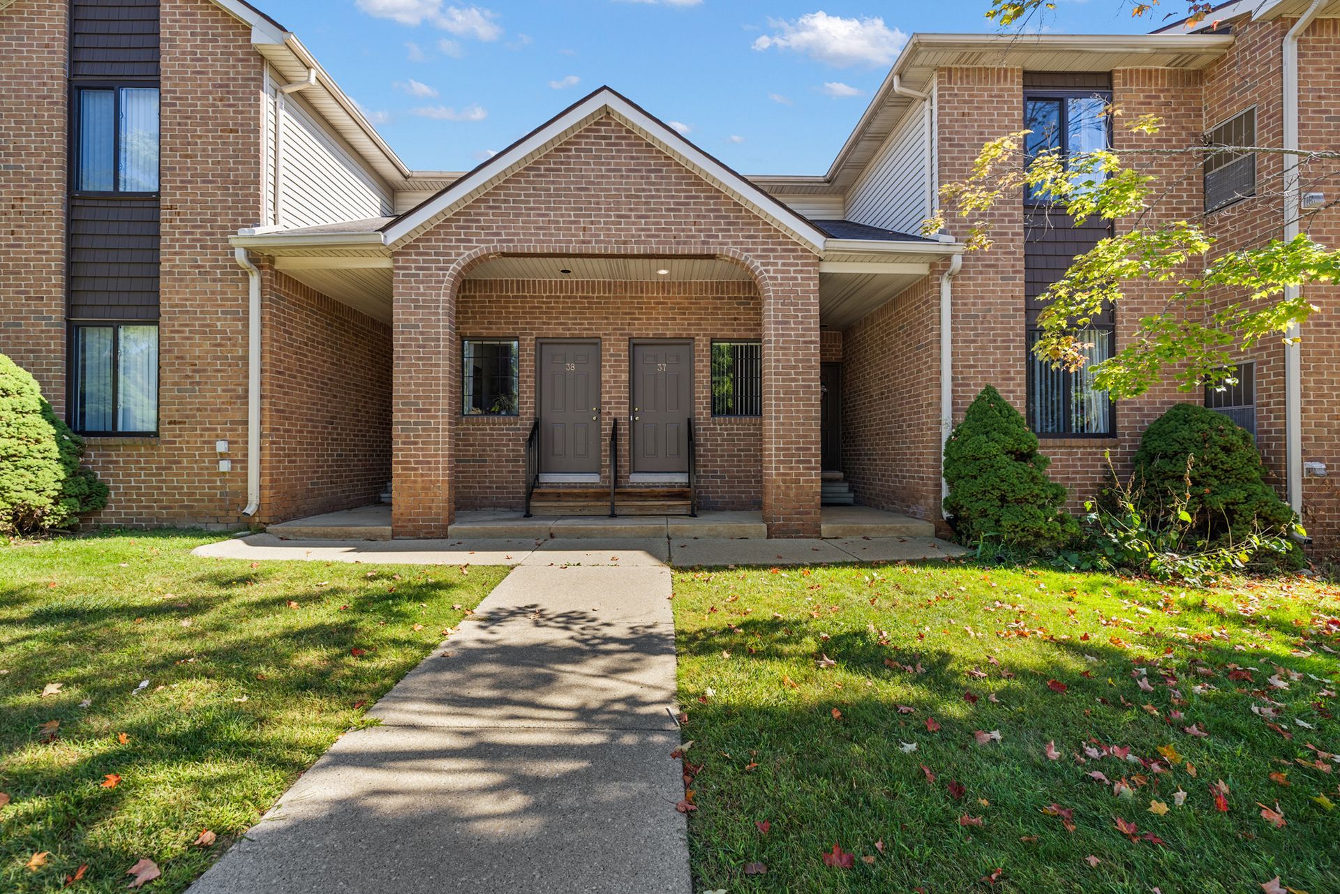 A brick apartment building with a walkway leading to it.