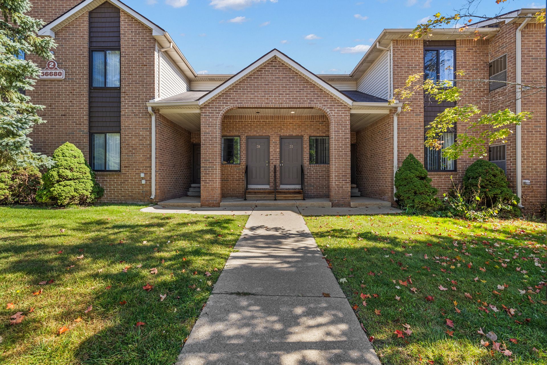 A brick apartment building with a walkway leading to the front door.