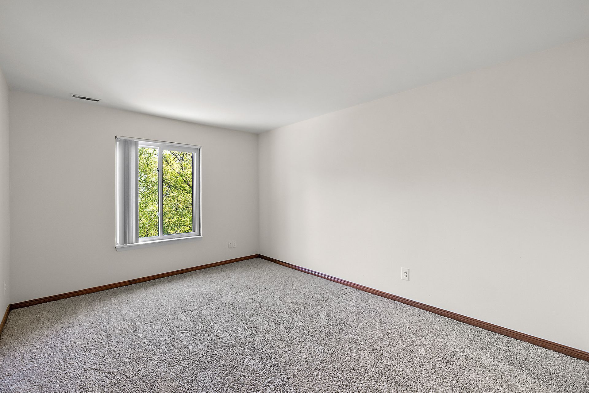 An empty room with a window and a carpeted floor.