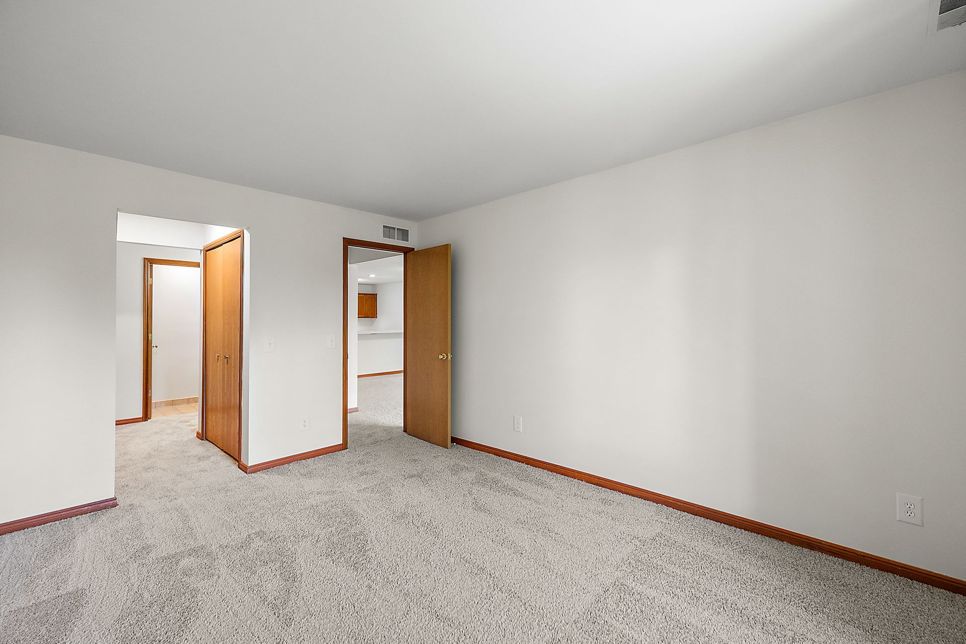 An empty living room with a carpeted floor and white walls.