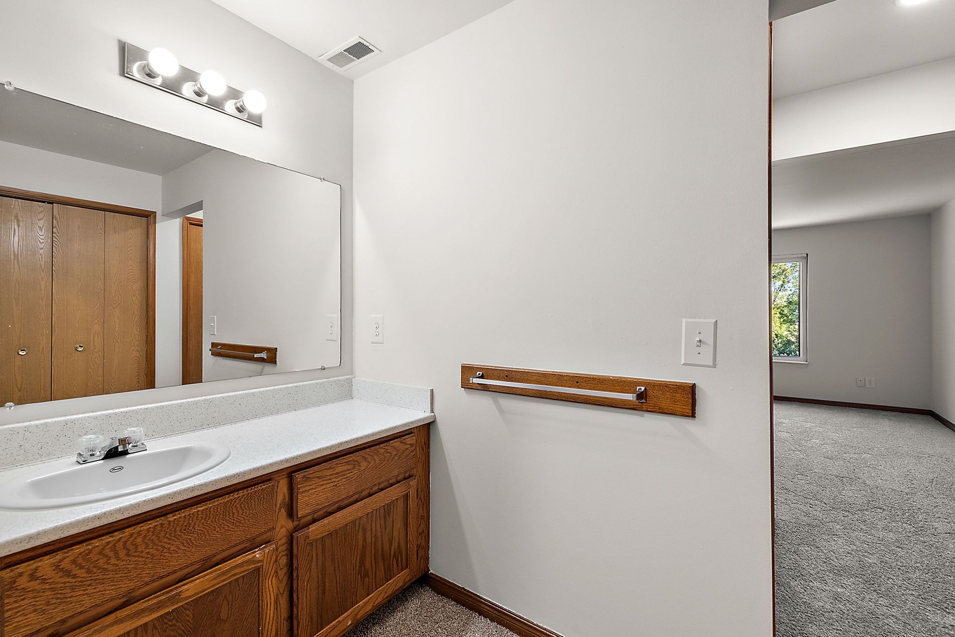 A bathroom with a sink , mirror and wooden cabinets.