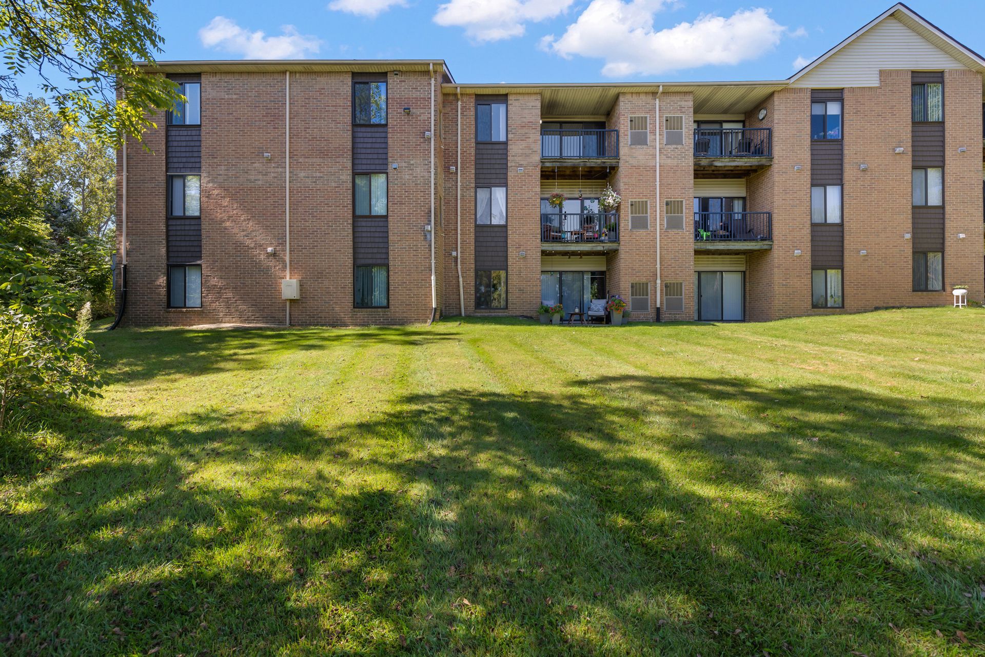A large brick apartment building with a lush green lawn in front of it.