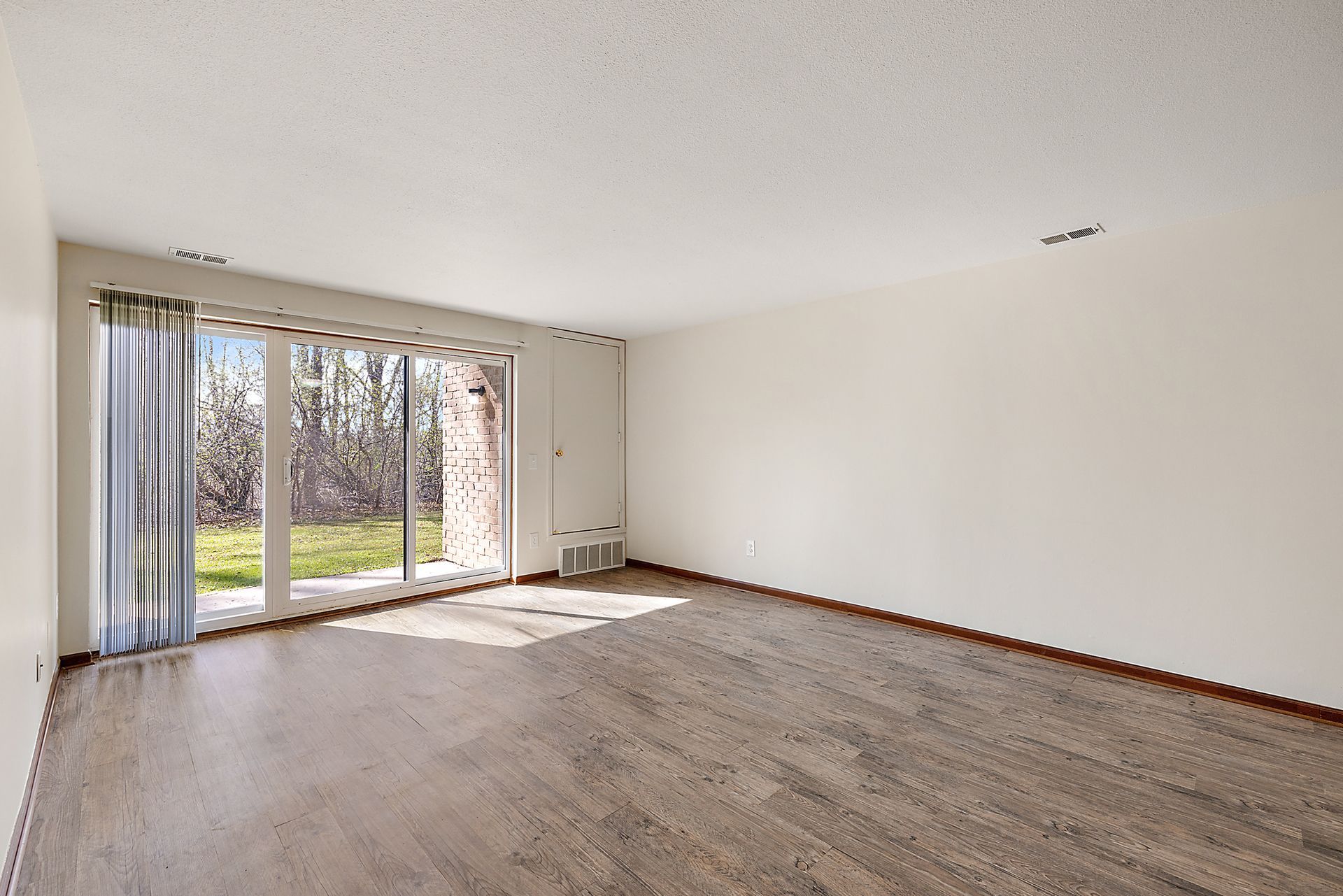 An empty living room with hardwood floors and sliding glass doors