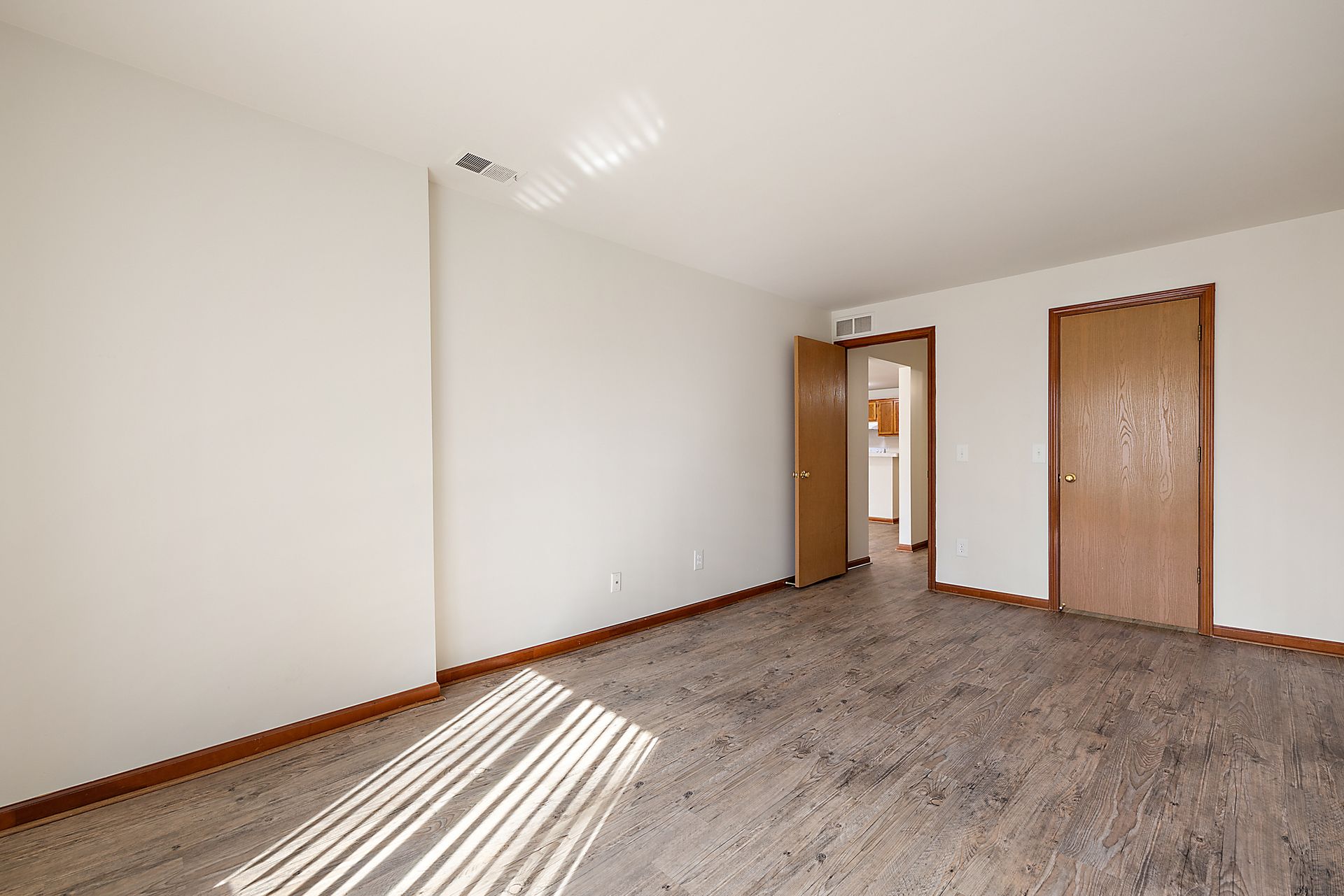 An empty room with a carpeted floor and white walls