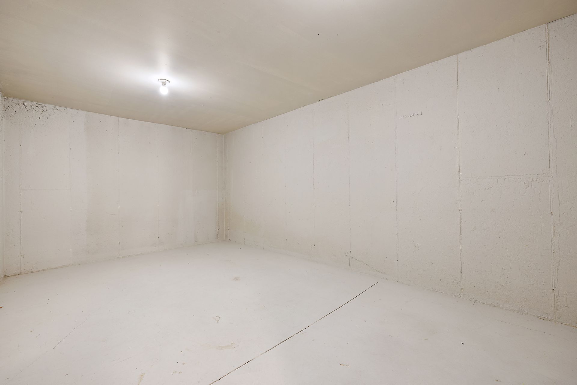 An empty room with white walls and a light on the ceiling.