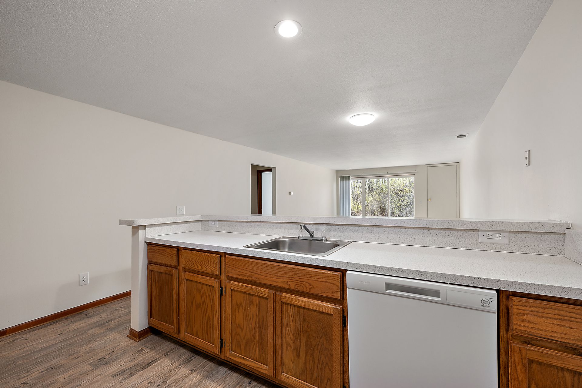 A kitchen with wooden cabinets , a sink , and a dishwasher.