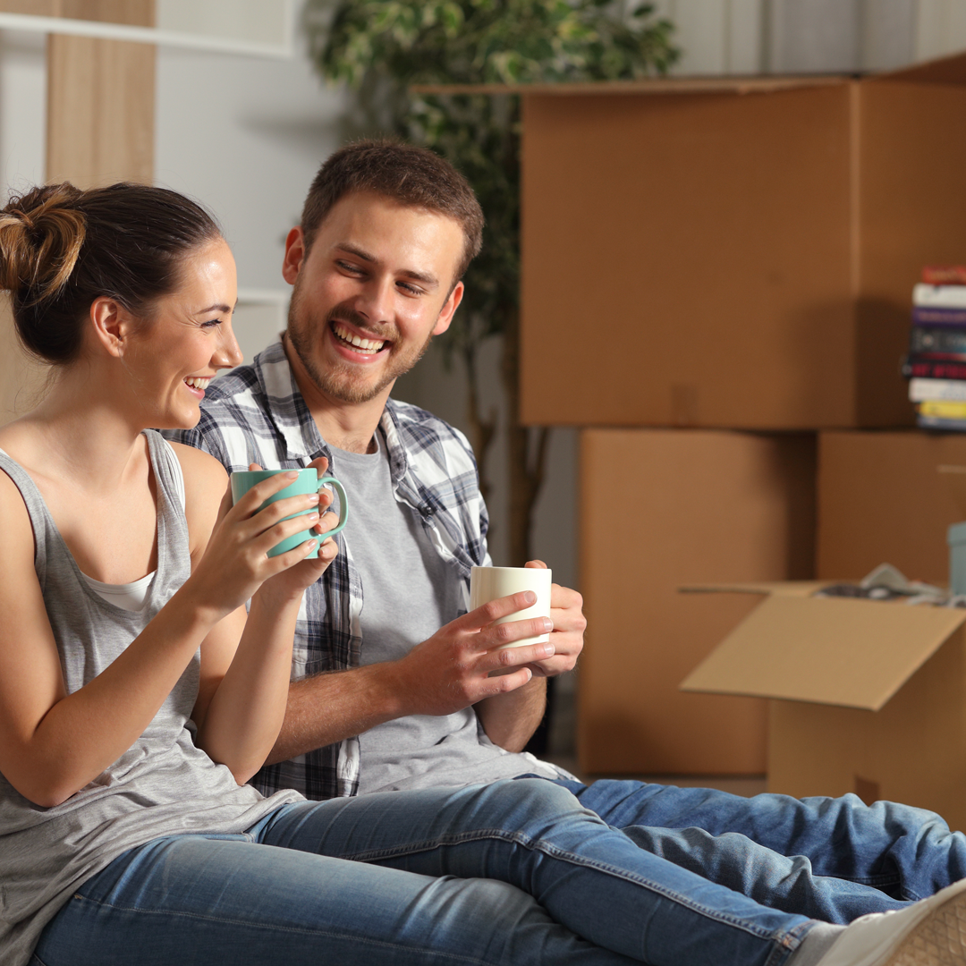 A man and a woman are sitting on the floor drinking coffee.