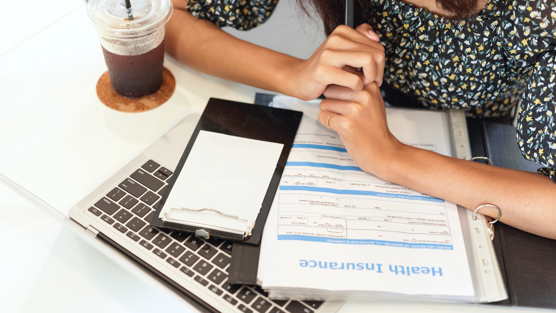 A woman is sitting at a table with a laptop and a cell phone.