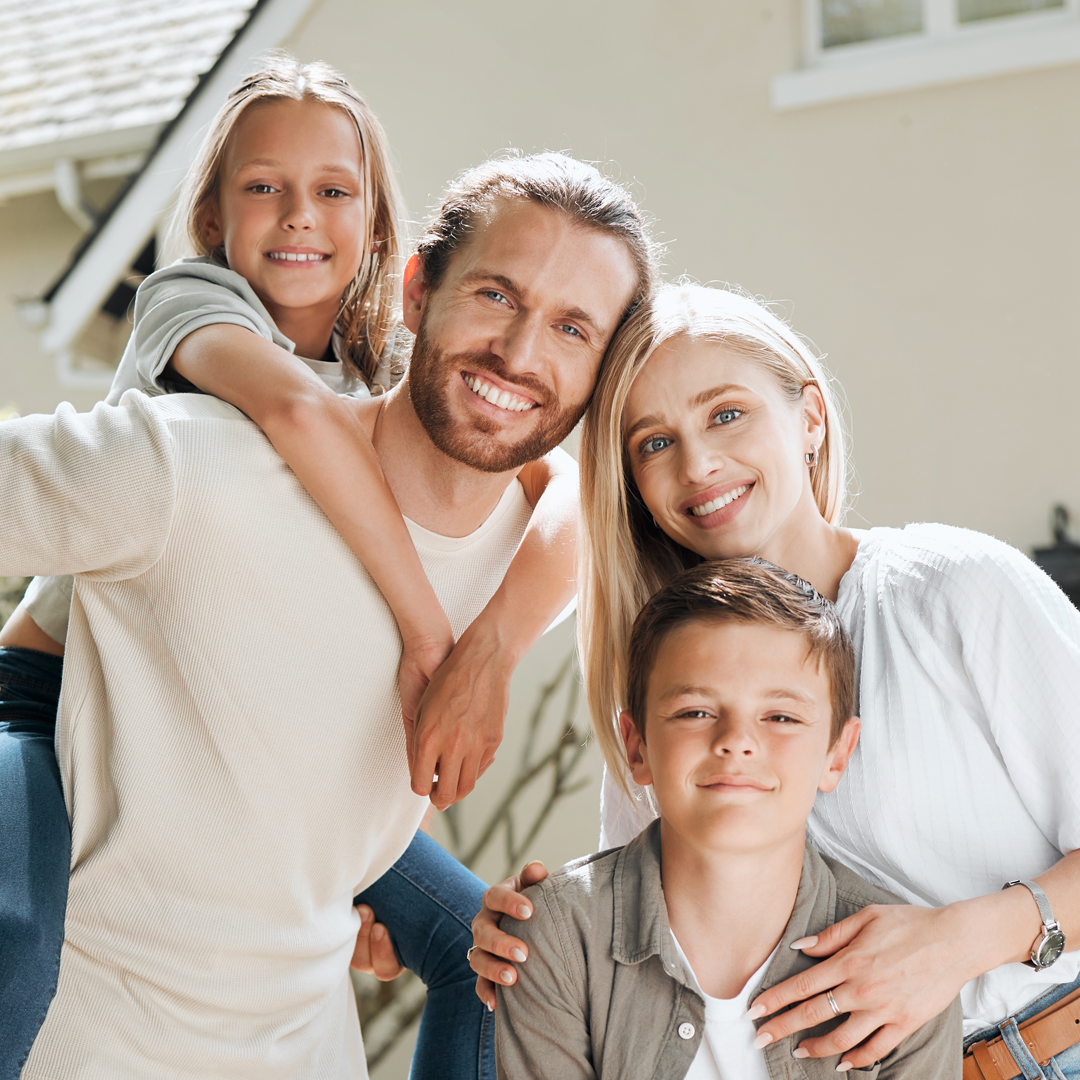 A family is posing for a picture in front of a house.