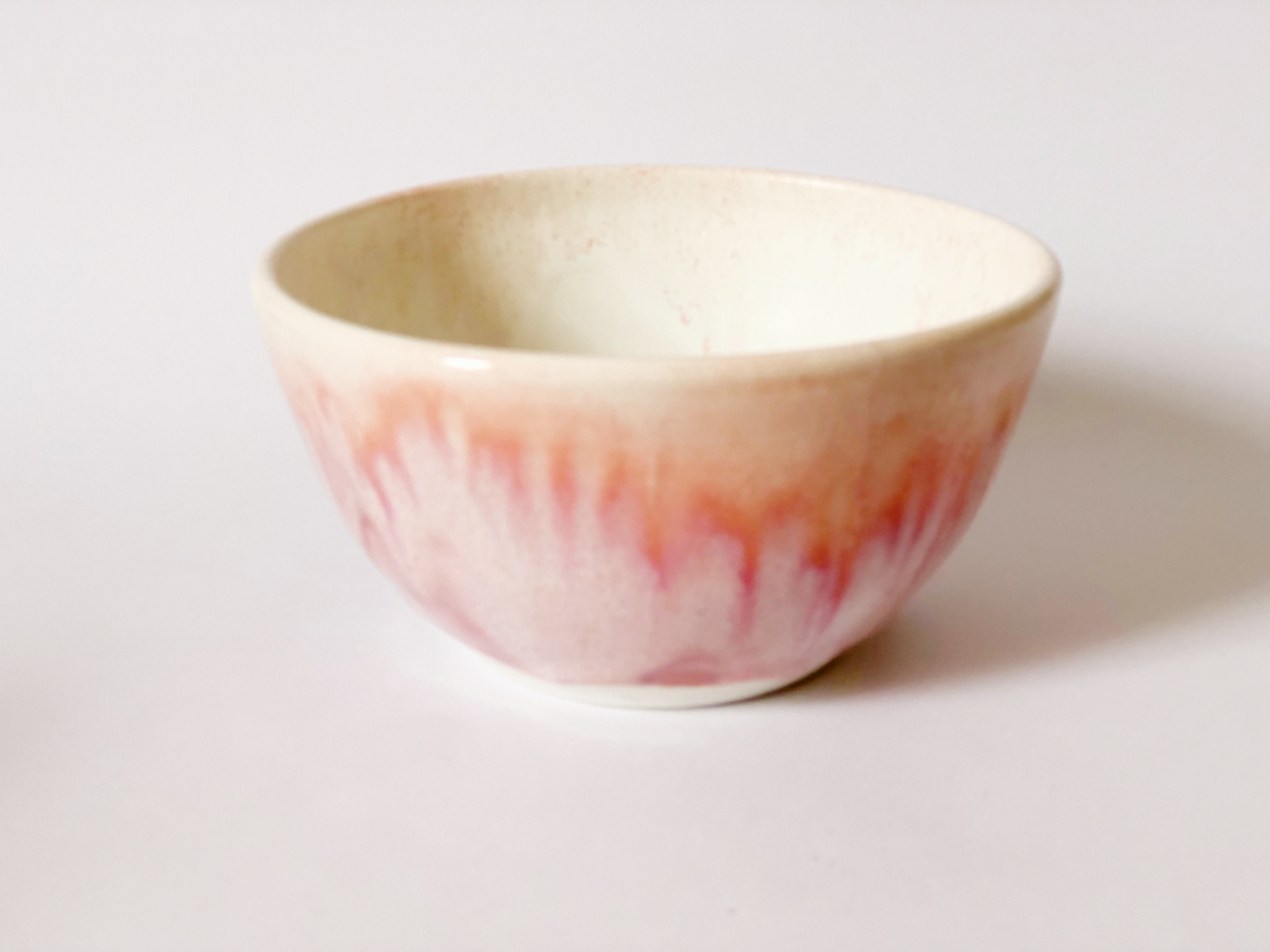 A pink and white bowl is sitting on a white surface.