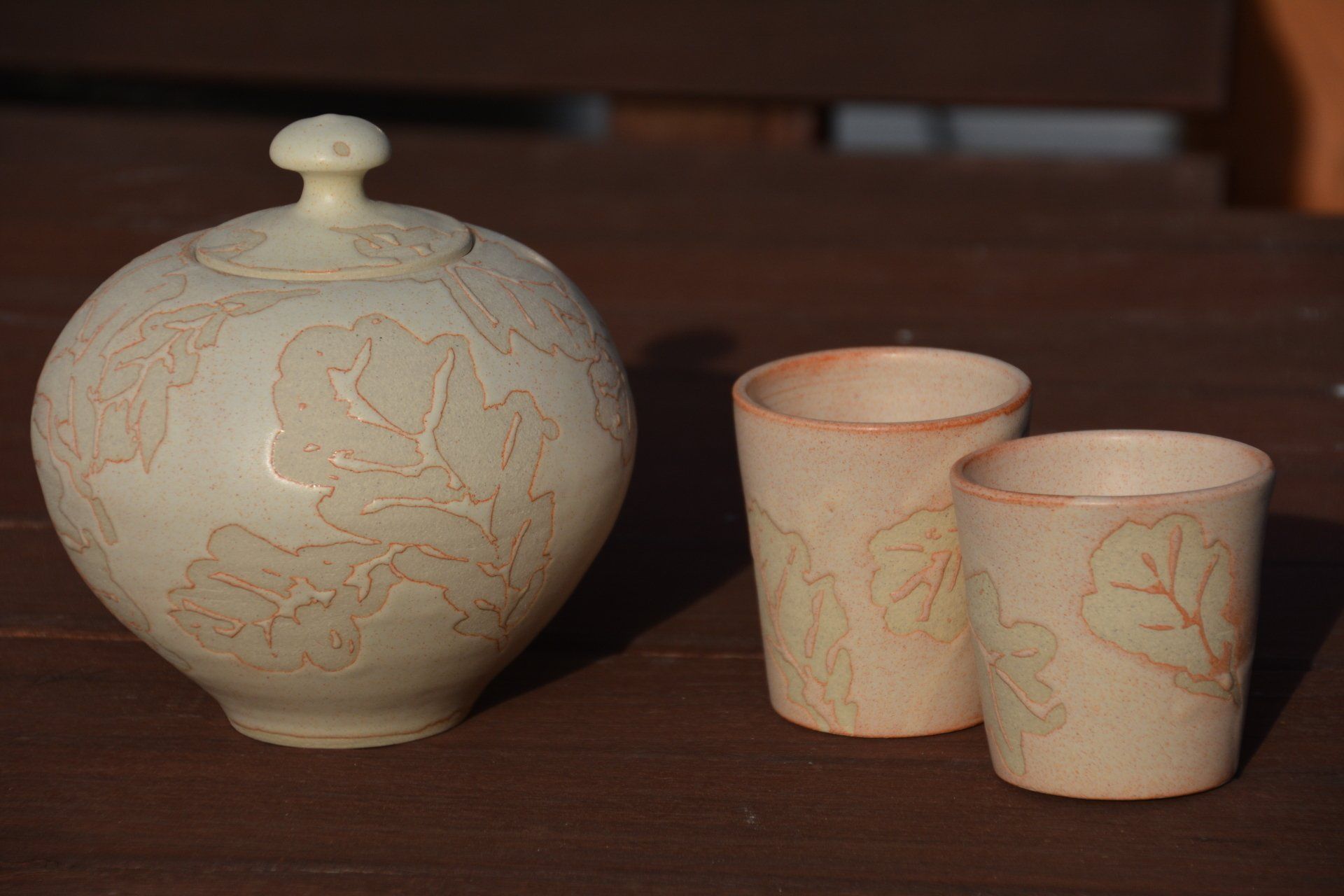 A vase and two cups are on a table