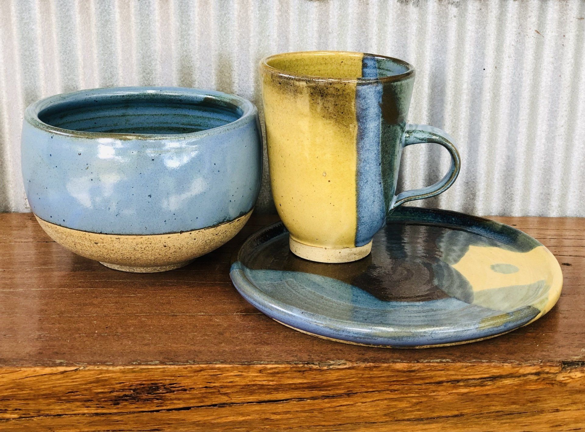 A blue and yellow cup and saucer are sitting on a wooden table.