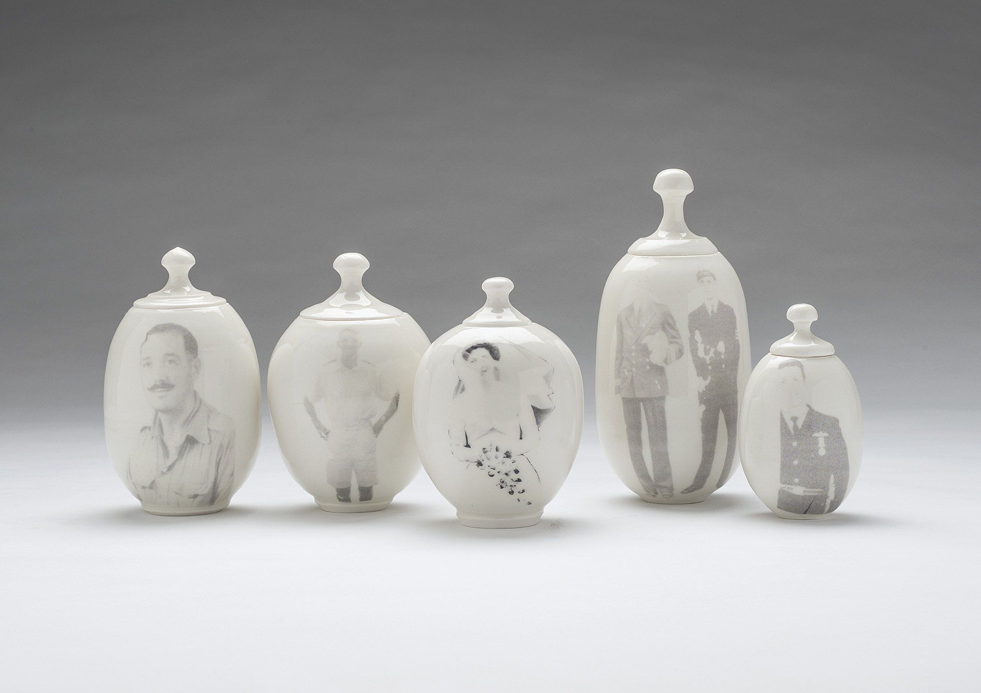 A group of porcelain containers with pictures on them are lined up on a table.