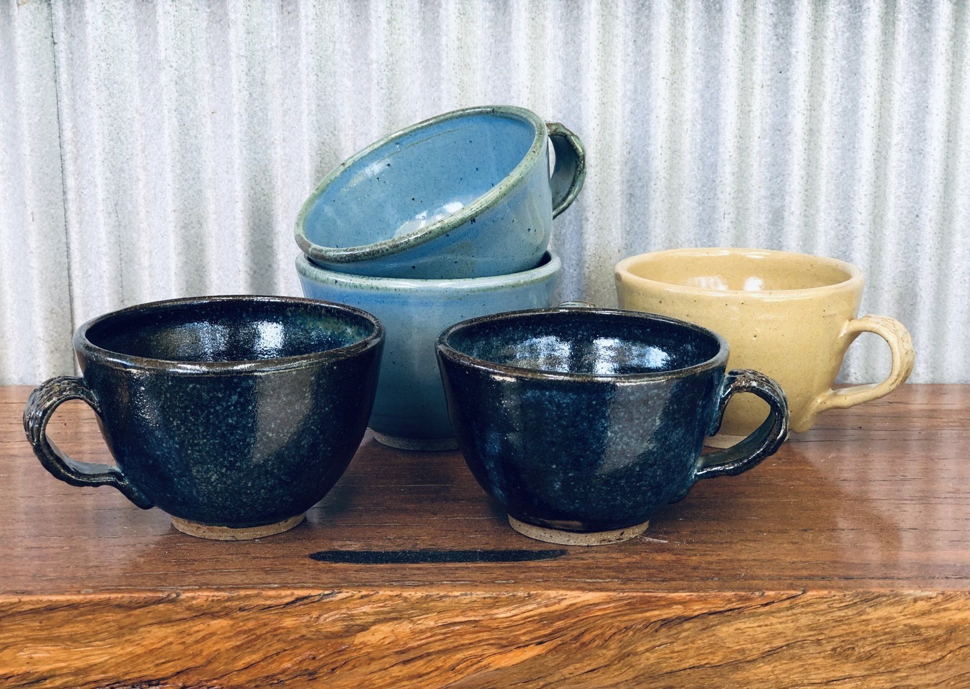 A group of coffee cups sitting on top of a wooden table.