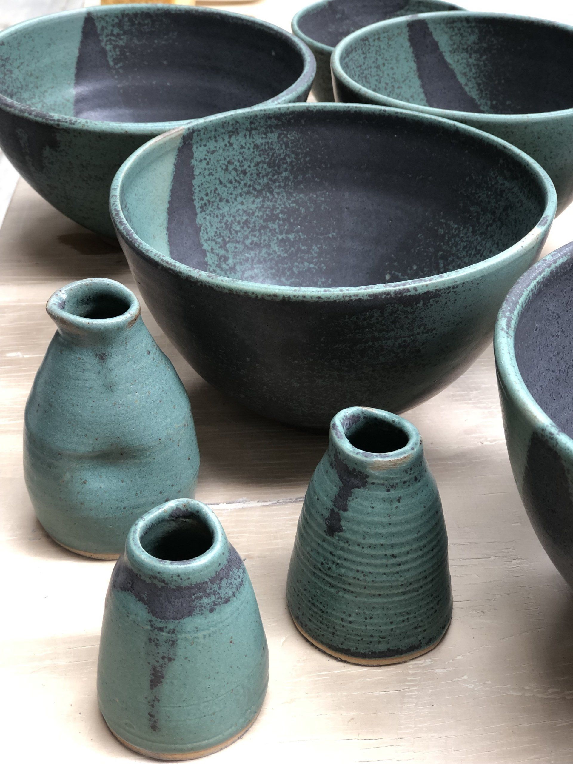 A group of bowls and vases are sitting on a table.