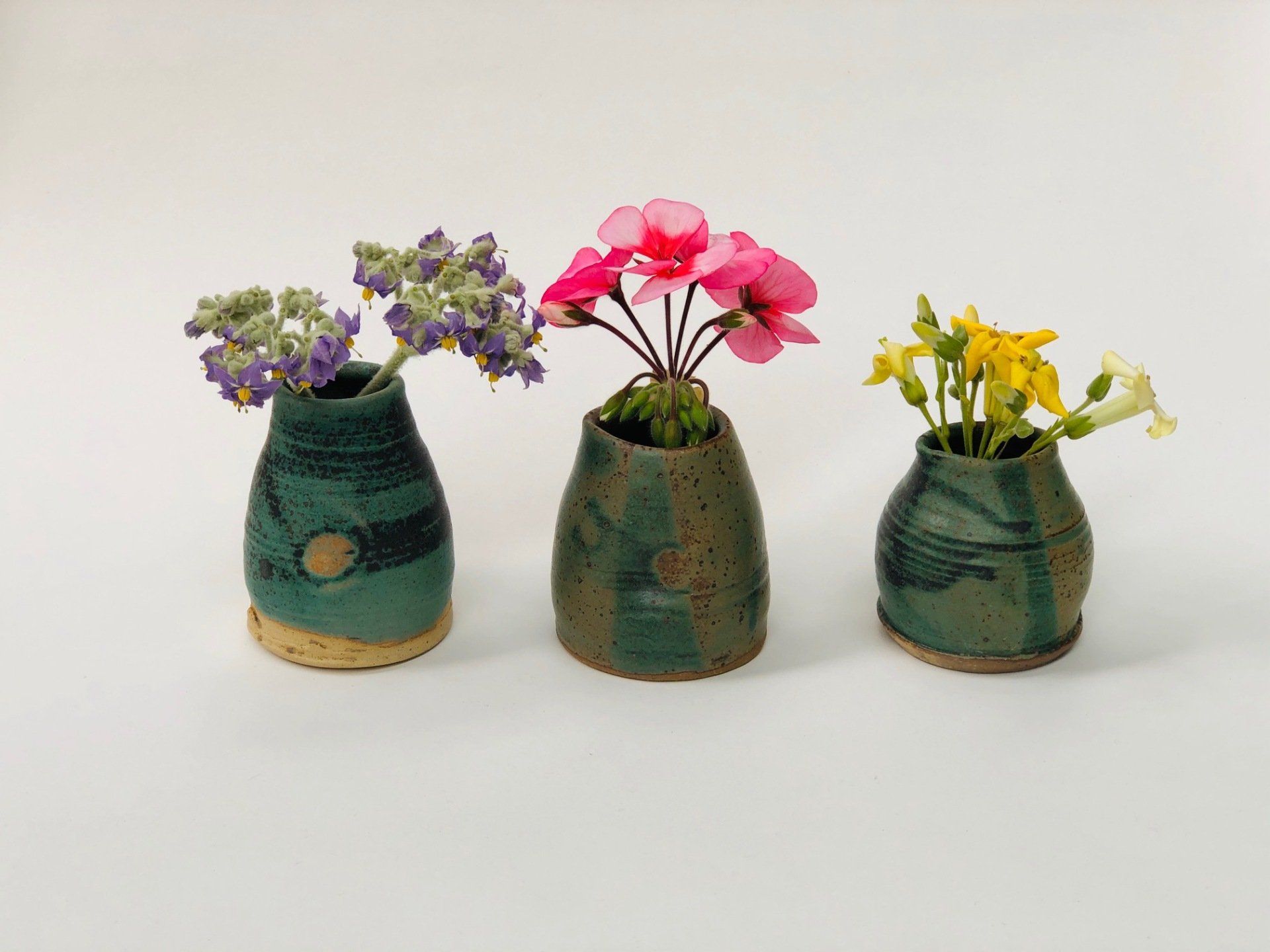Three vases with flowers in them are lined up on a table