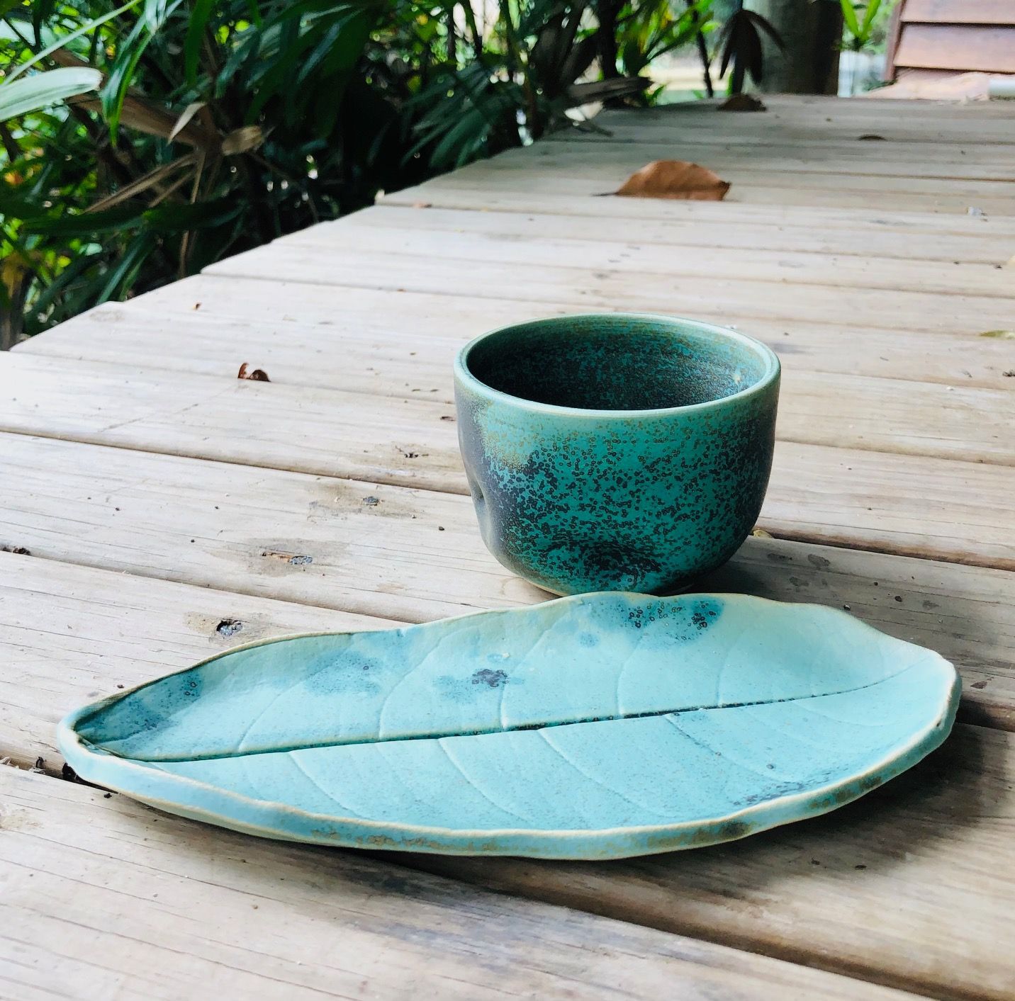 A leaf shaped plate and cup on a wooden table